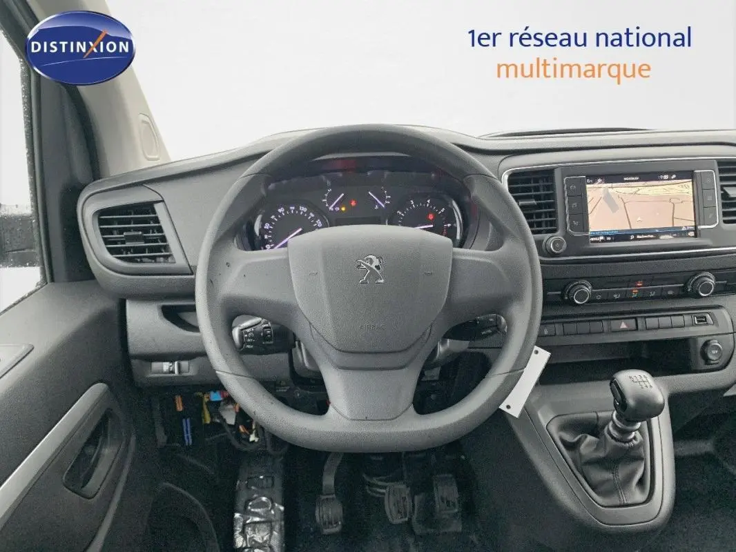 Vue intérieure centrée sur le volant Peugeot et le tableau de bord avec écran tactile et levier de vitesse manuel.