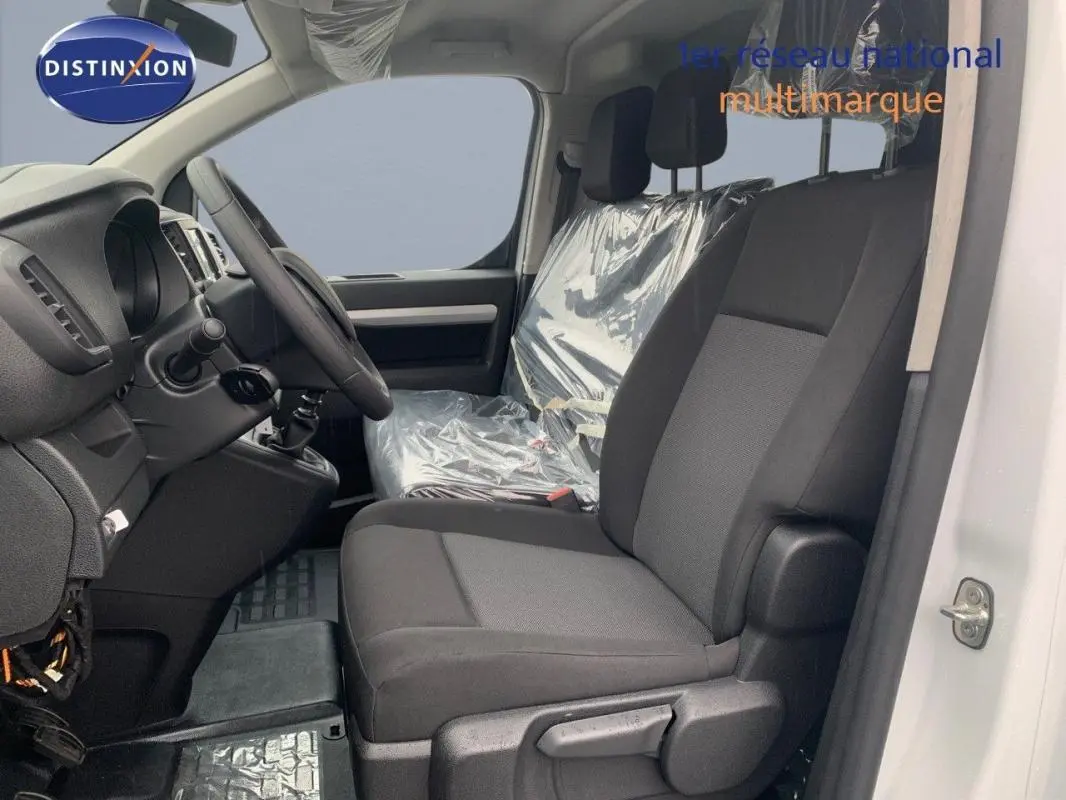 Vue intérieure côté conducteur du Peugeot Expert Fourgon blanc 2023, montrant les sièges avant et le tableau de bord.