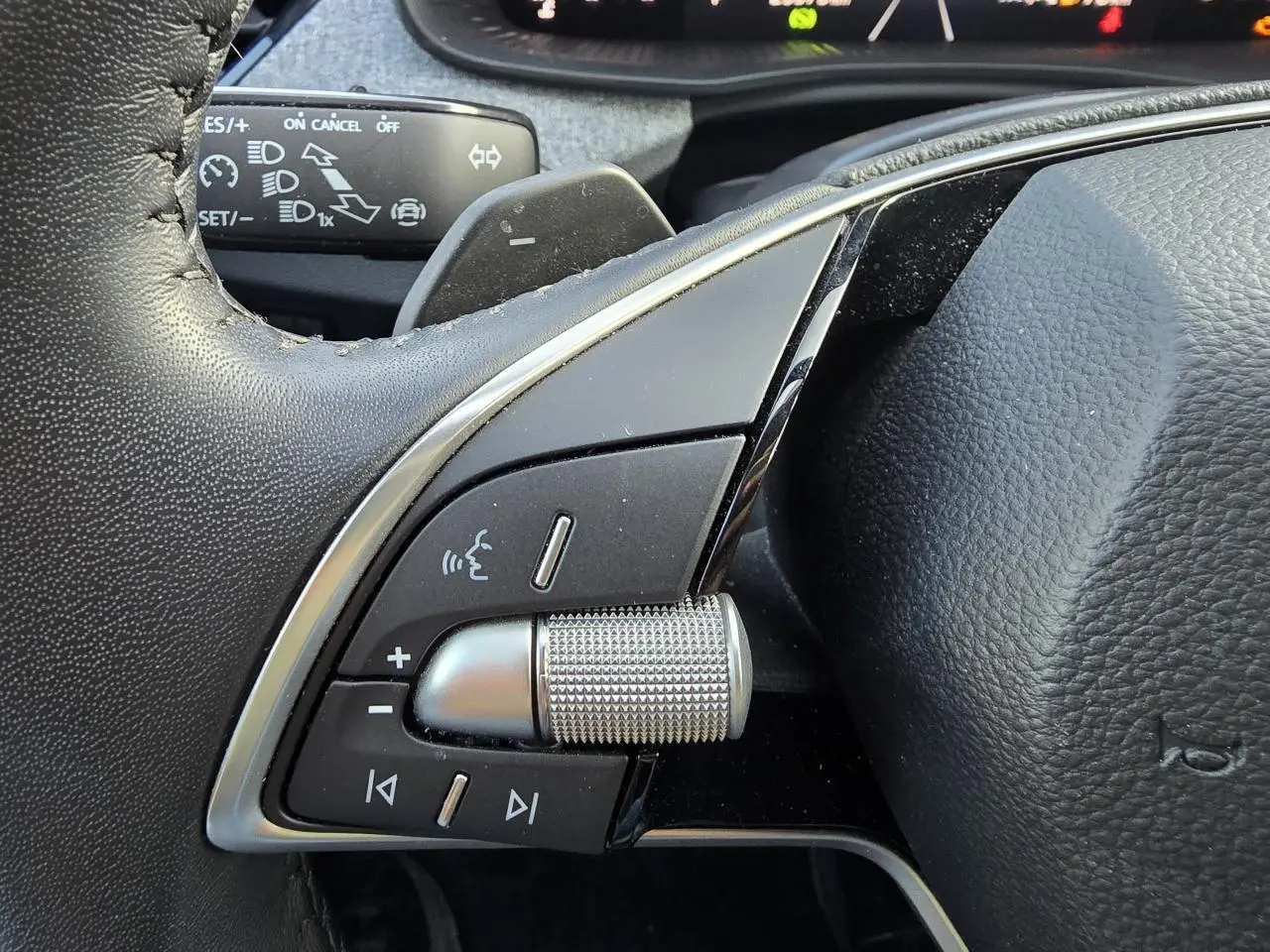 Gros plan sur les commandes multifonctions argentées du volant noir du Skoda Scala gris graphite 2024.