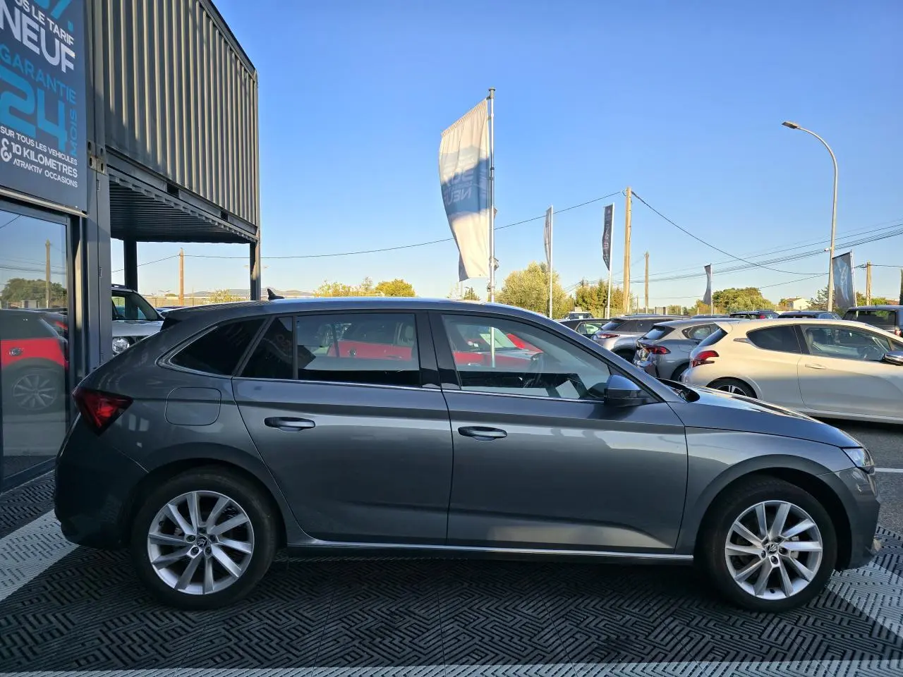 Profil côté gauche d'une Skoda Scala gris graphite métal avec jantes alliage 17 pouces, stationnée en extérieur.