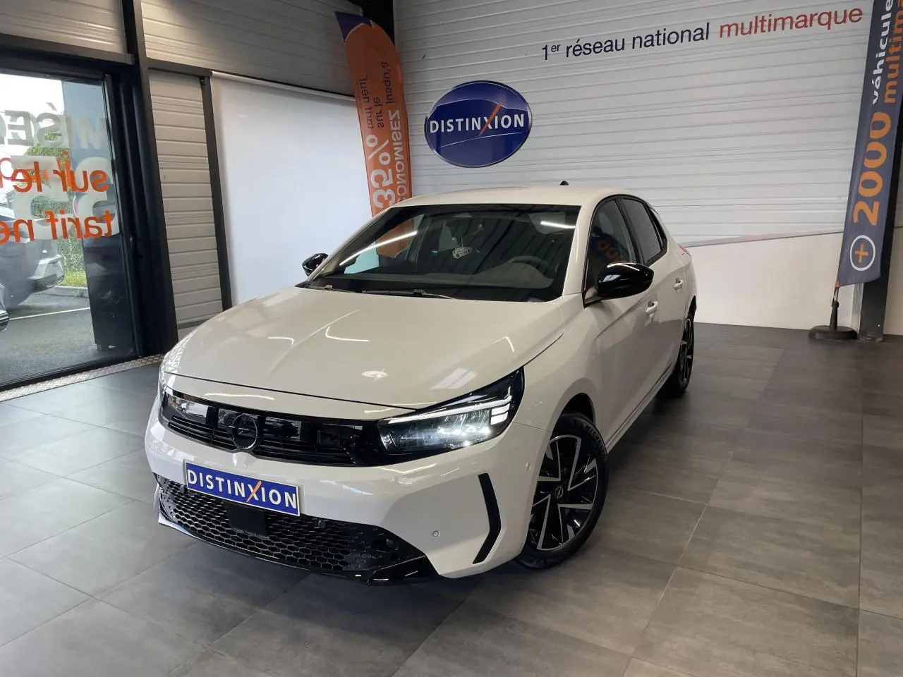 Vue 3/4 avant droite d'une Opel Corsa blanche avec calandre noire et jantes alliage noires diamantées en showroom.