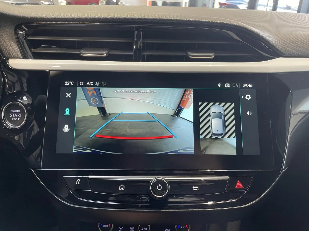 Écran tactile central affichant la caméra de recul panoramique dans l'habitacle noir d'une Opel Corsa blanche.