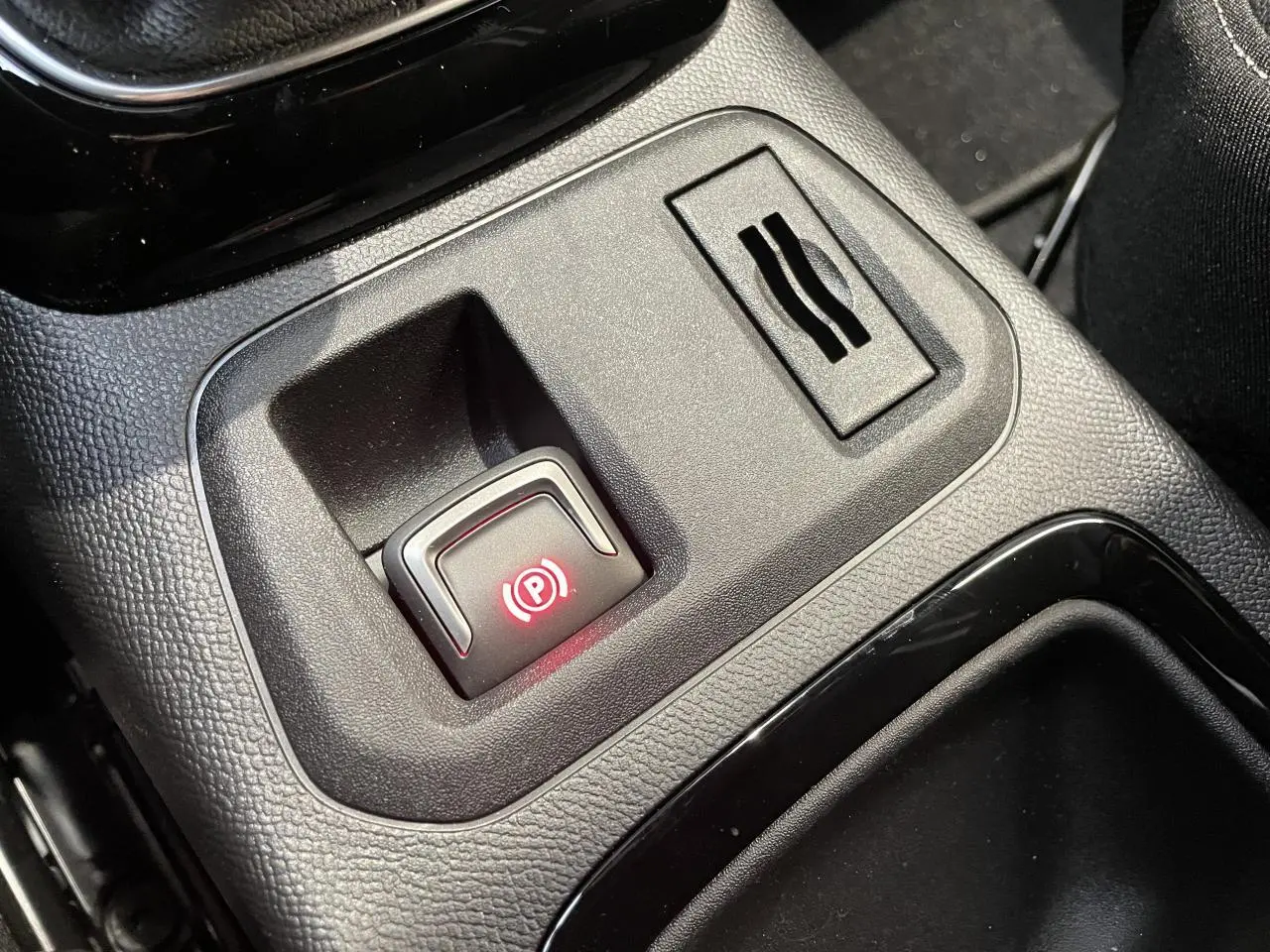 Gros plan sur le frein de parking électrique allumé dans la console centrale noire de l'Opel Corsa 2026.