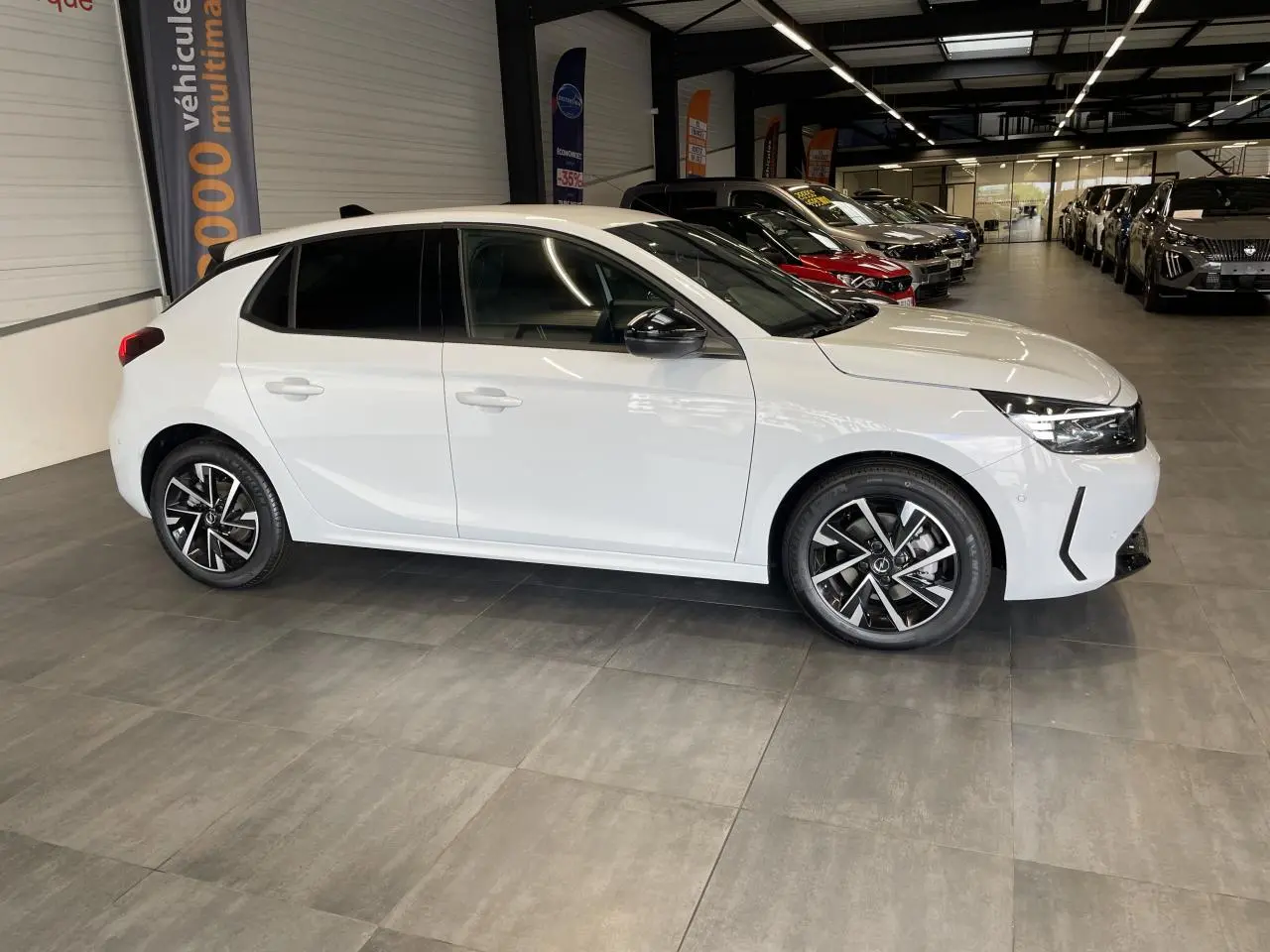 Opel Corsa blanche vue de profil côté gauche en intérieur, avec jantes alliage et vitres teintées.