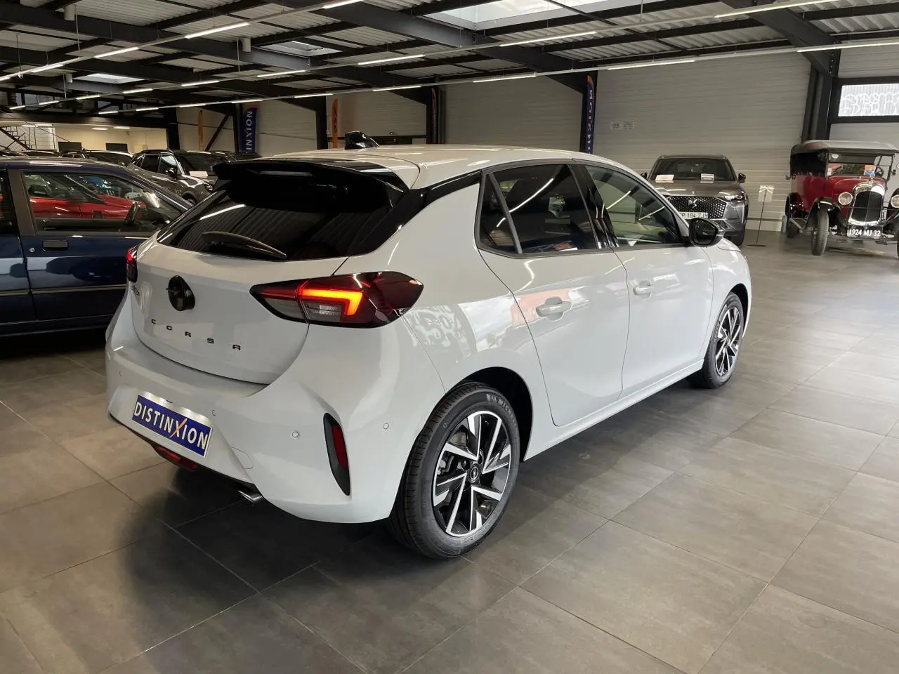 Opel Corsa blanche vue 3/4 arrière droit en intérieur, avec feux arrière LED et jantes alliage diamantées.
