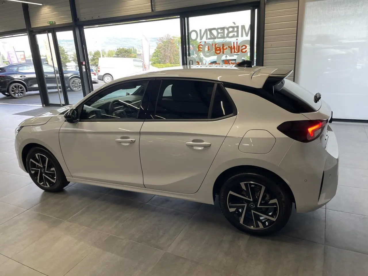 Opel Corsa blanche vue de profil côté gauche, vitres arrière surteintées et jantes alliage noires diamantées.