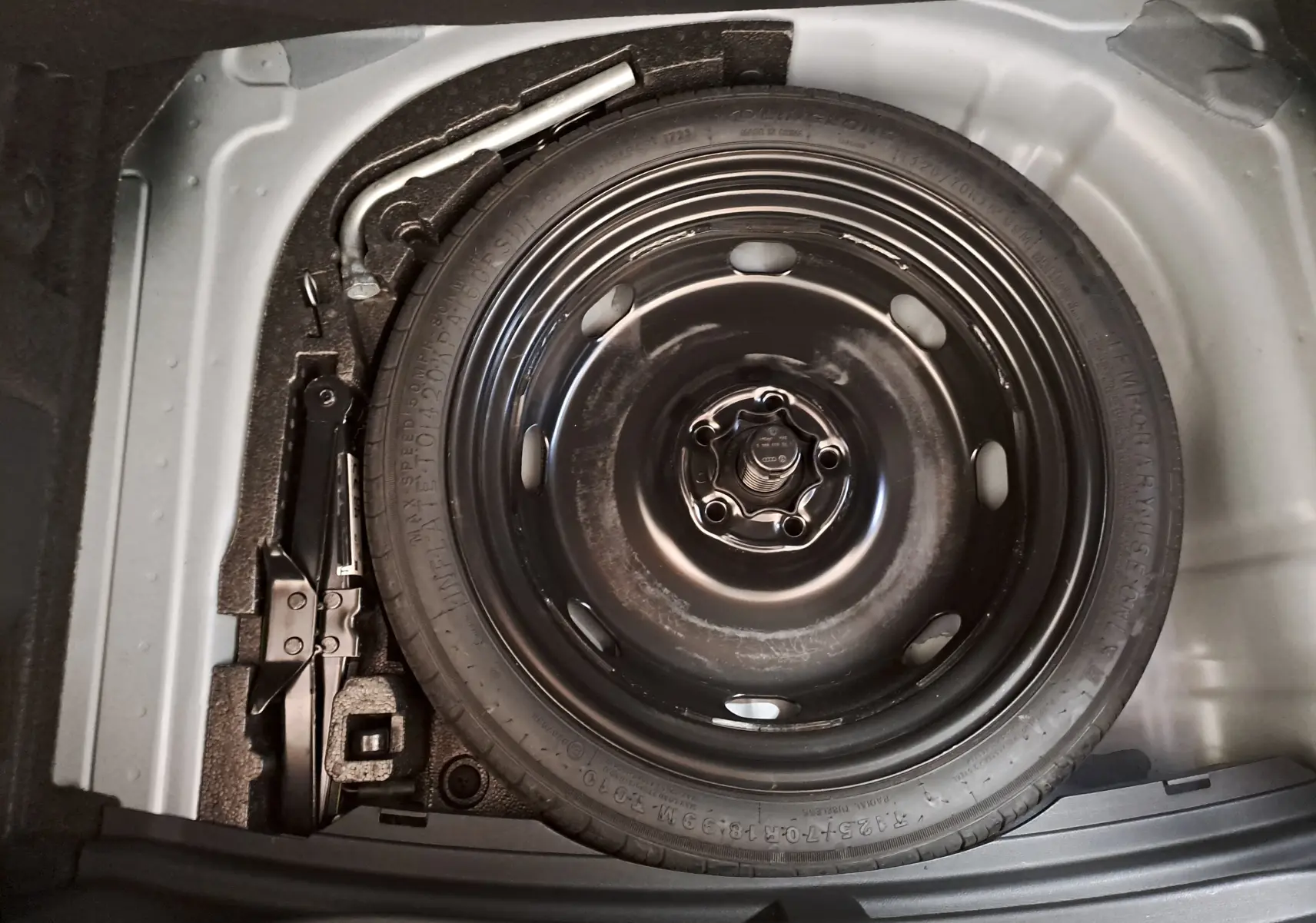 Vue en plongée sur la roue de secours et le cric dans le coffre d'une CUPRA Leon 2024, gris magnétique mat.