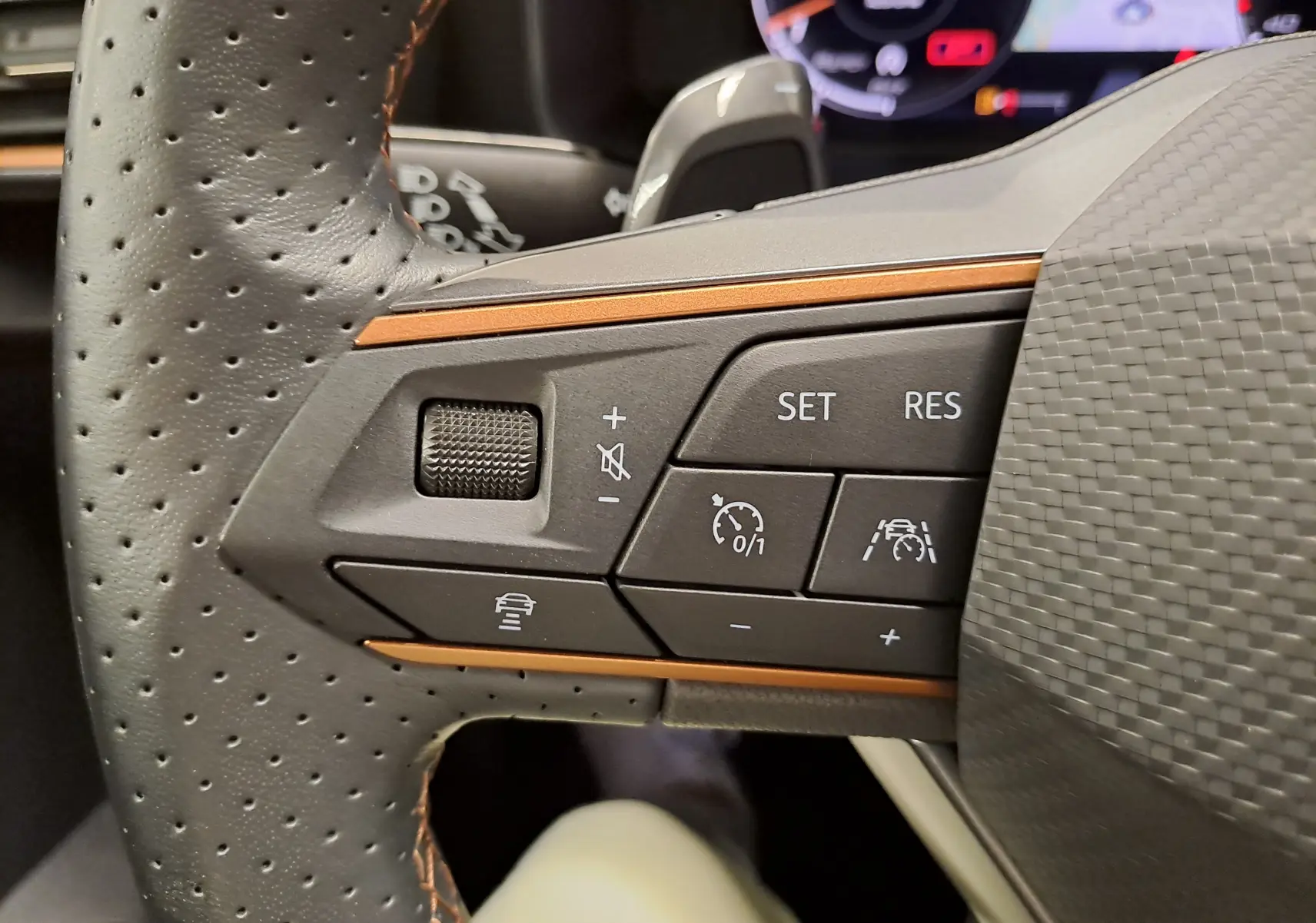 Gros plan sur les commandes de régulateur de vitesse au volant perforé d’une CUPRA Leon 2024 avec surpiqûres cuivrées.