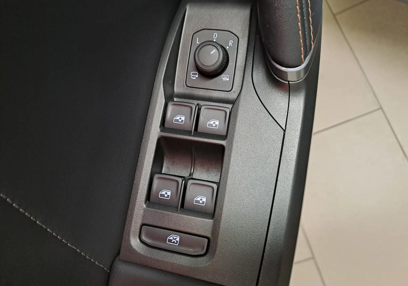 Gros plan sur les commandes des vitres électriques et rétroviseurs côté conducteur d’une CUPRA Leon 2024 finition Gris Magnétique Mat.