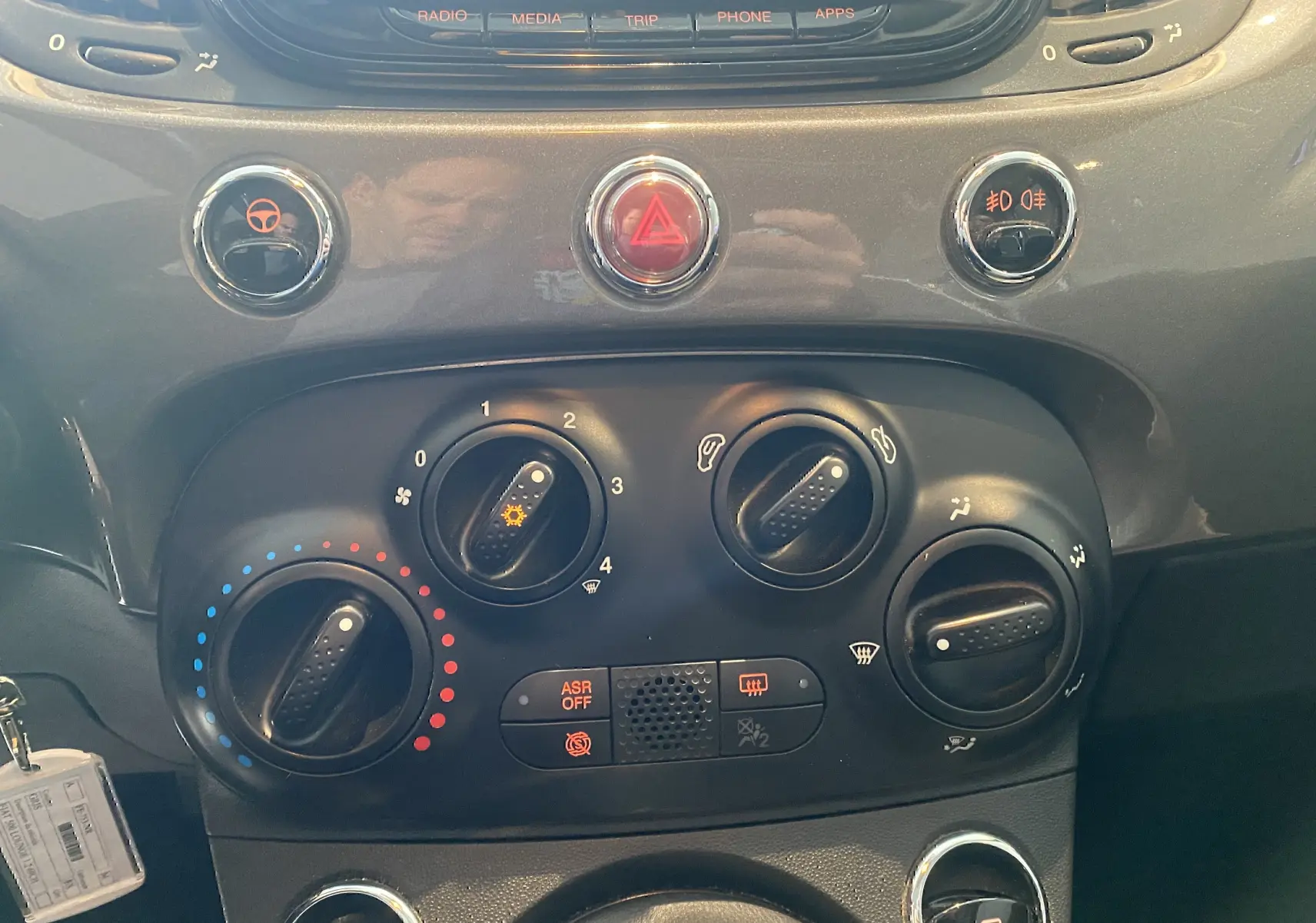 Vue rapprochée du tableau de bord gris foncé de la Fiat 500 2019, avec commandes de climatisation et boutons lumineux.