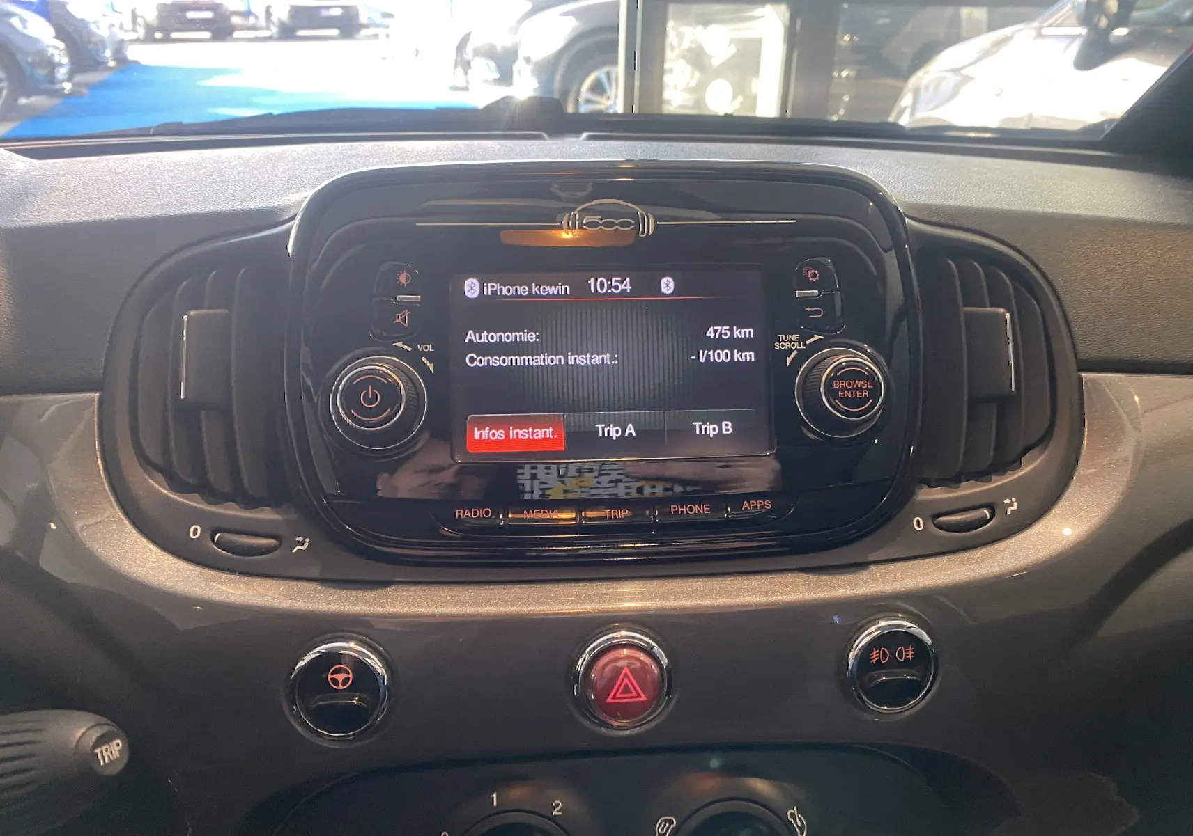 Tableau de bord de Fiat 500 gris foncé, vue frontale centrée sur l’écran multimédia avec commandes autour.