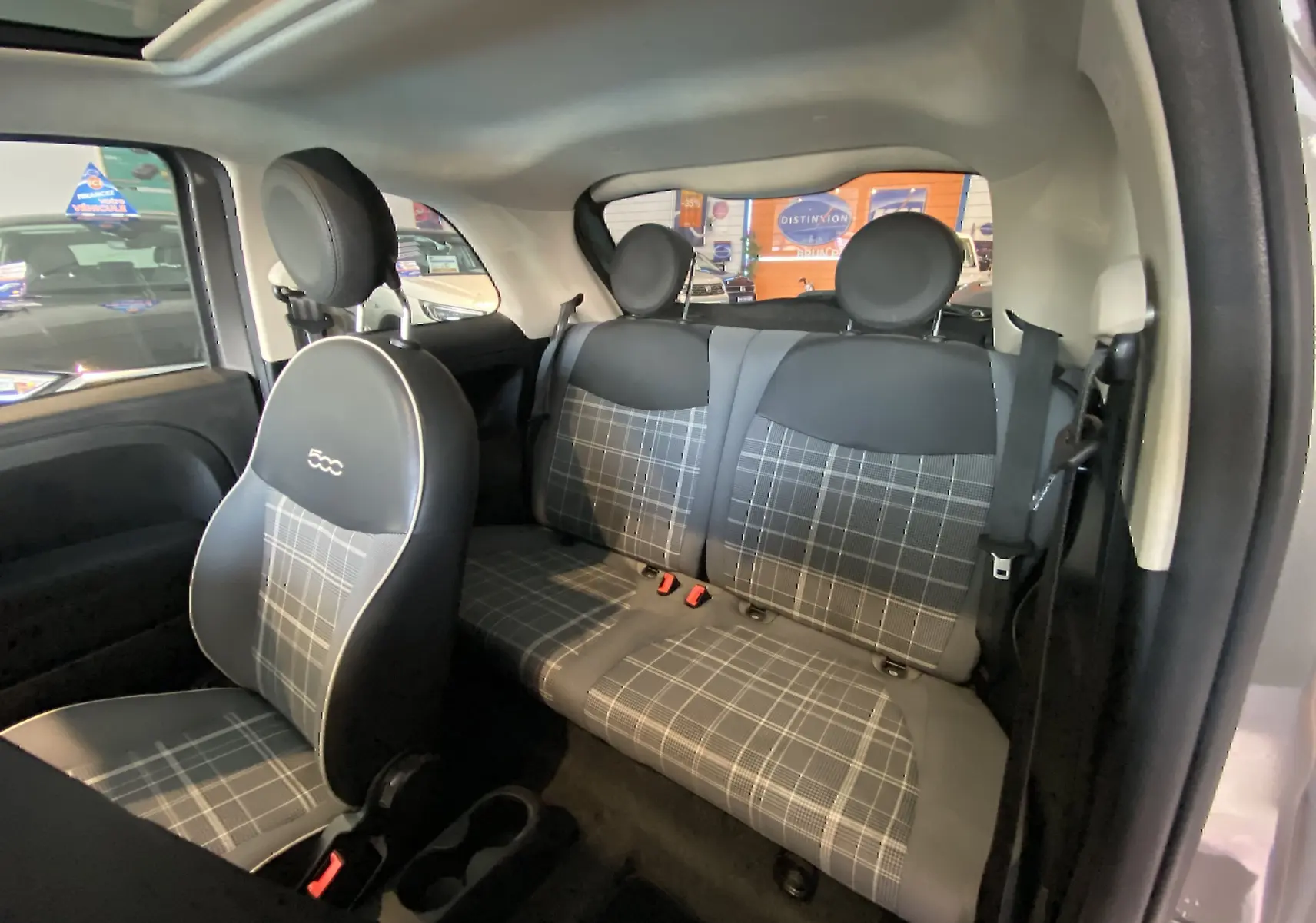 Vue intérieure côté droit de la FIAT 500 1.2 8V Lounge 2019 avec sièges en tissu à motif carreaux gris et noir.