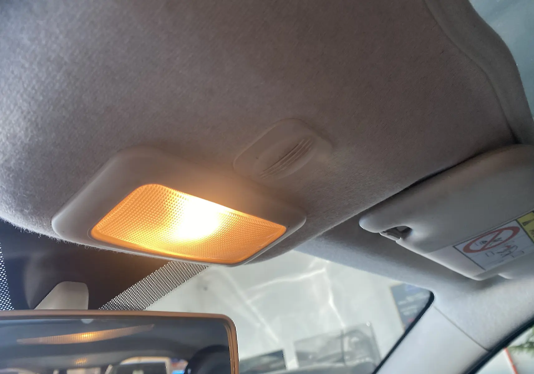 Plafonnier intérieur allumé et pare-soleil côté droit dans l’habitacle gris foncé d’une Fiat 500 Lounge 2019.