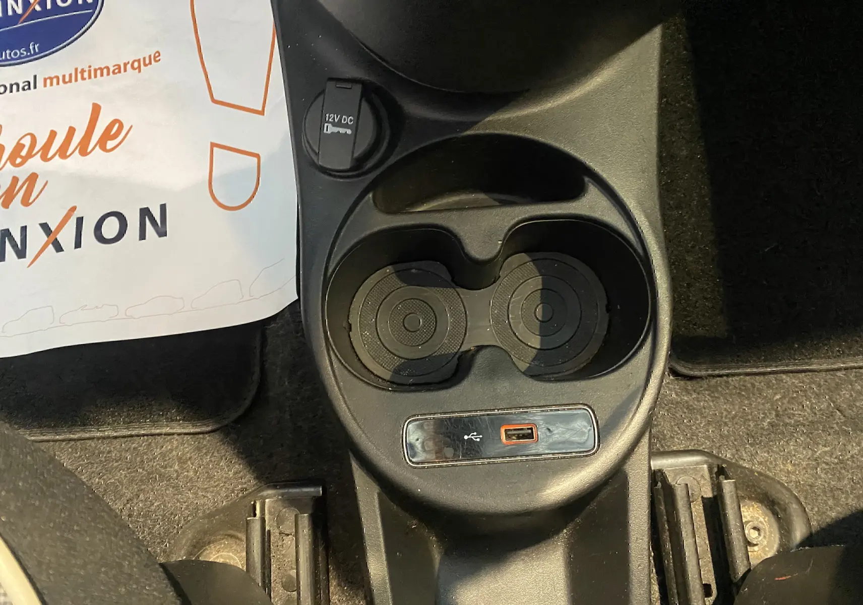 Gros plan sur la console centrale noire de la Fiat 500 gris foncé, avec porte-gobelets et prise USB visible.