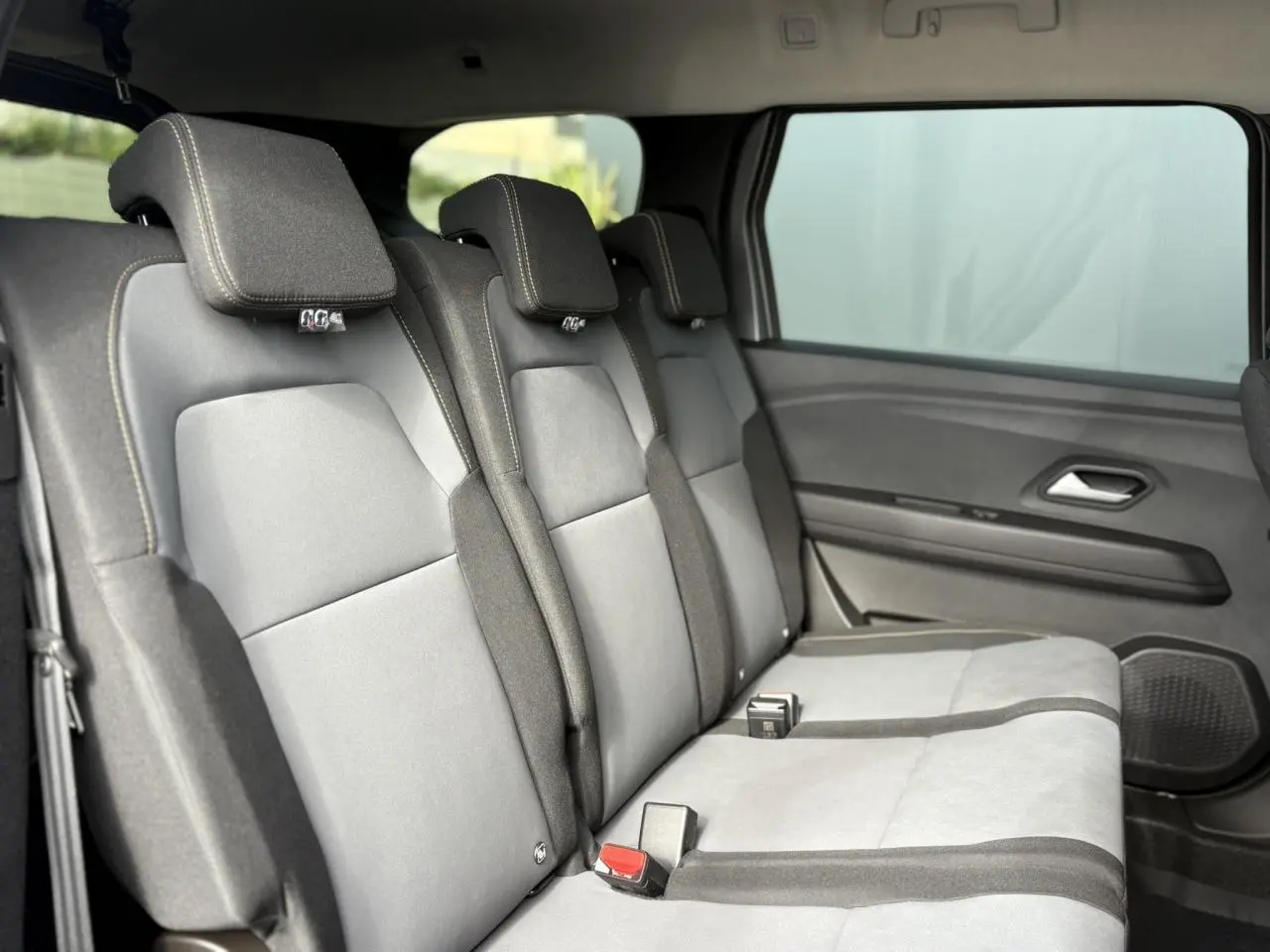 Vue latérale droite des sièges arrière gris clair et foncé du Dacia Jogger 2024 dans un intérieur spacieux.