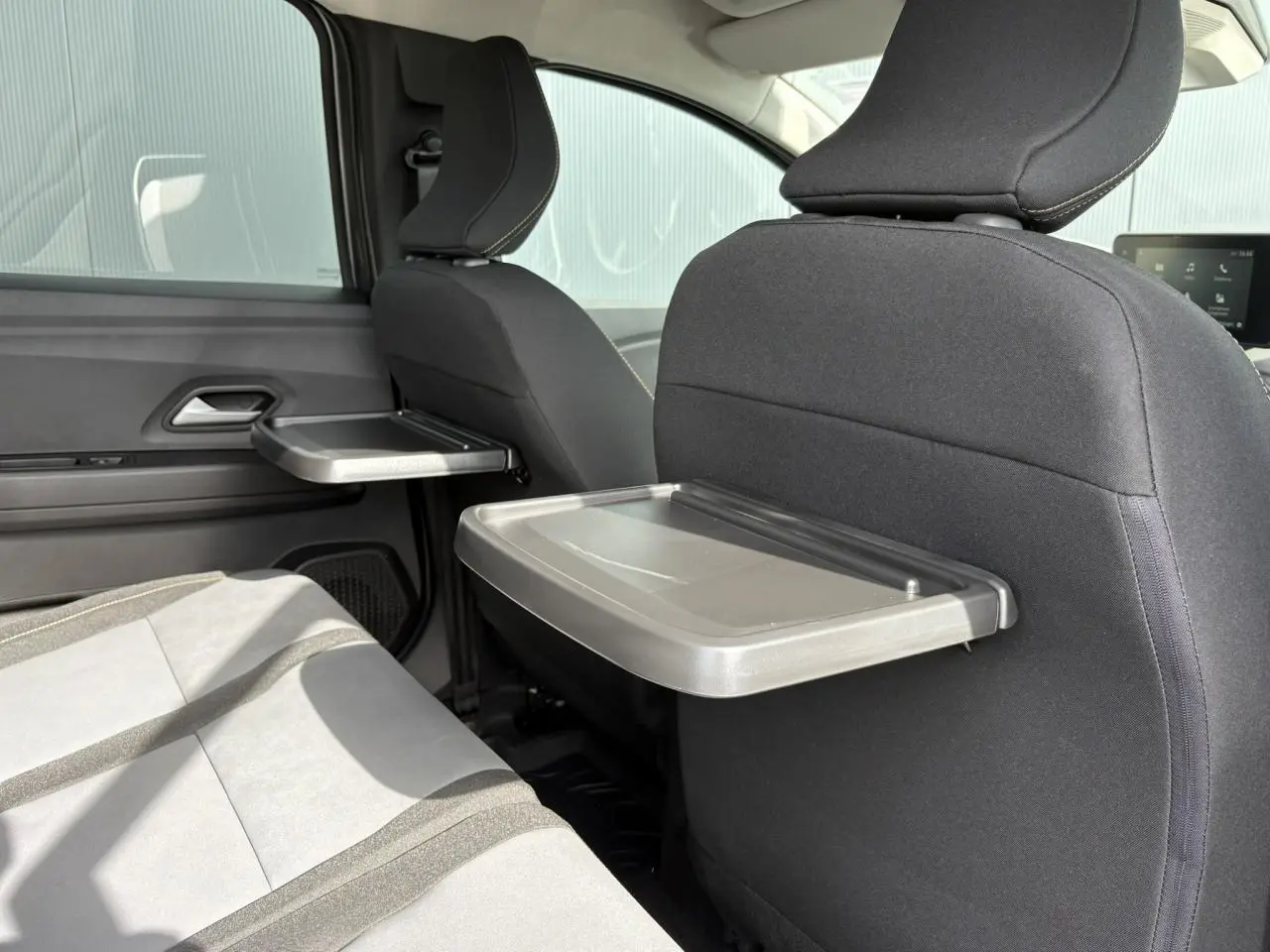Vue intérieure arrière du Dacia Jogger 2024 avec tablettes aviation déployées sur les dossiers des sièges avant.