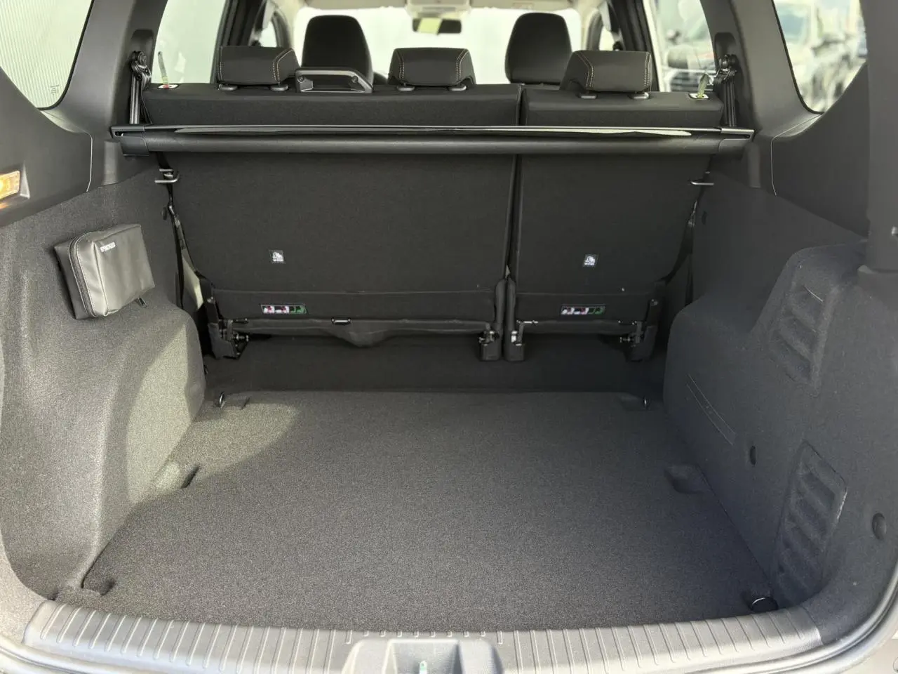 Coffre spacieux du Dacia Jogger ECO-G 100 Extreme+ vu de l'arrière, intérieur noir avec banquette rabattue.