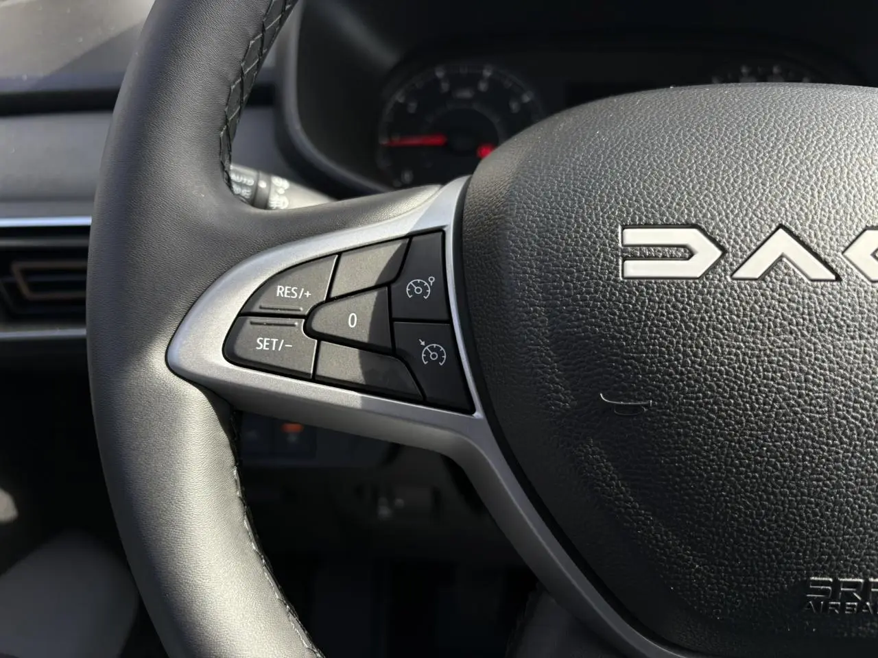 Gros plan sur le volant noir du Dacia Jogger 2024 avec commandes de régulateur de vitesse intégrées.