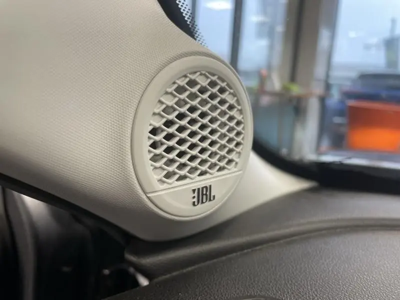 Gros plan sur le haut-parleur JBL beige intégré à l’intérieur de la Jeep Avenger 2025, côté gauche du tableau de bord.