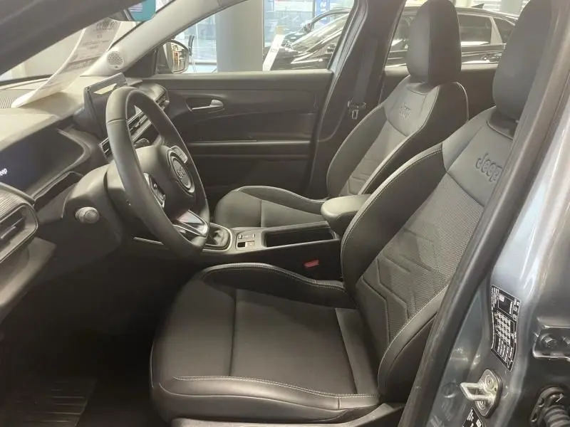 Vue intérieure côté conducteur du Jeep Avenger 2025, sièges noirs avec logo Jeep brodé et tableau de bord moderne.