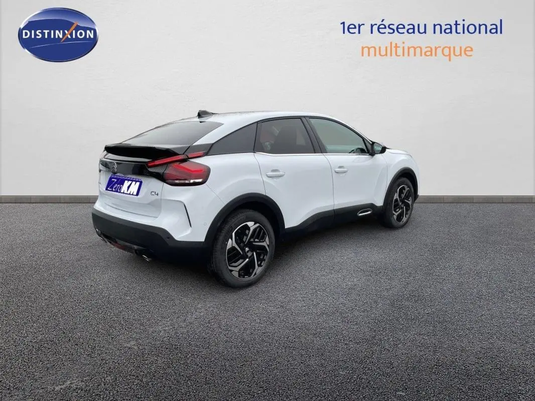 Vue 3/4 arrière droite d'une Citroën C4 blanche 2024 avec jantes aluminium et toit noir contrasté.