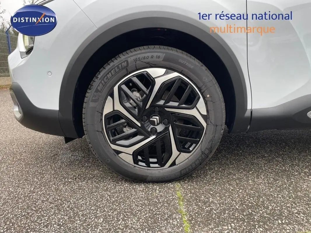 Gros plan sur la roue avant droite avec jante aluminium noire et argentée du Citroën C4 blanc 2024.