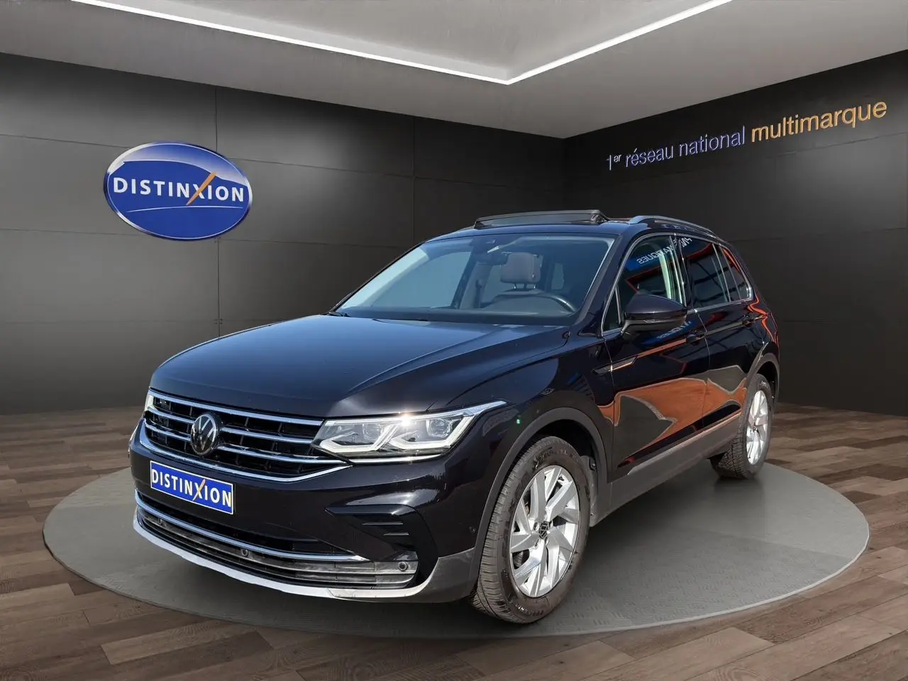 Volkswagen Tiguan noir intense en 3/4 avant droit, jantes alu 18 pouces et toit panoramique visible.
