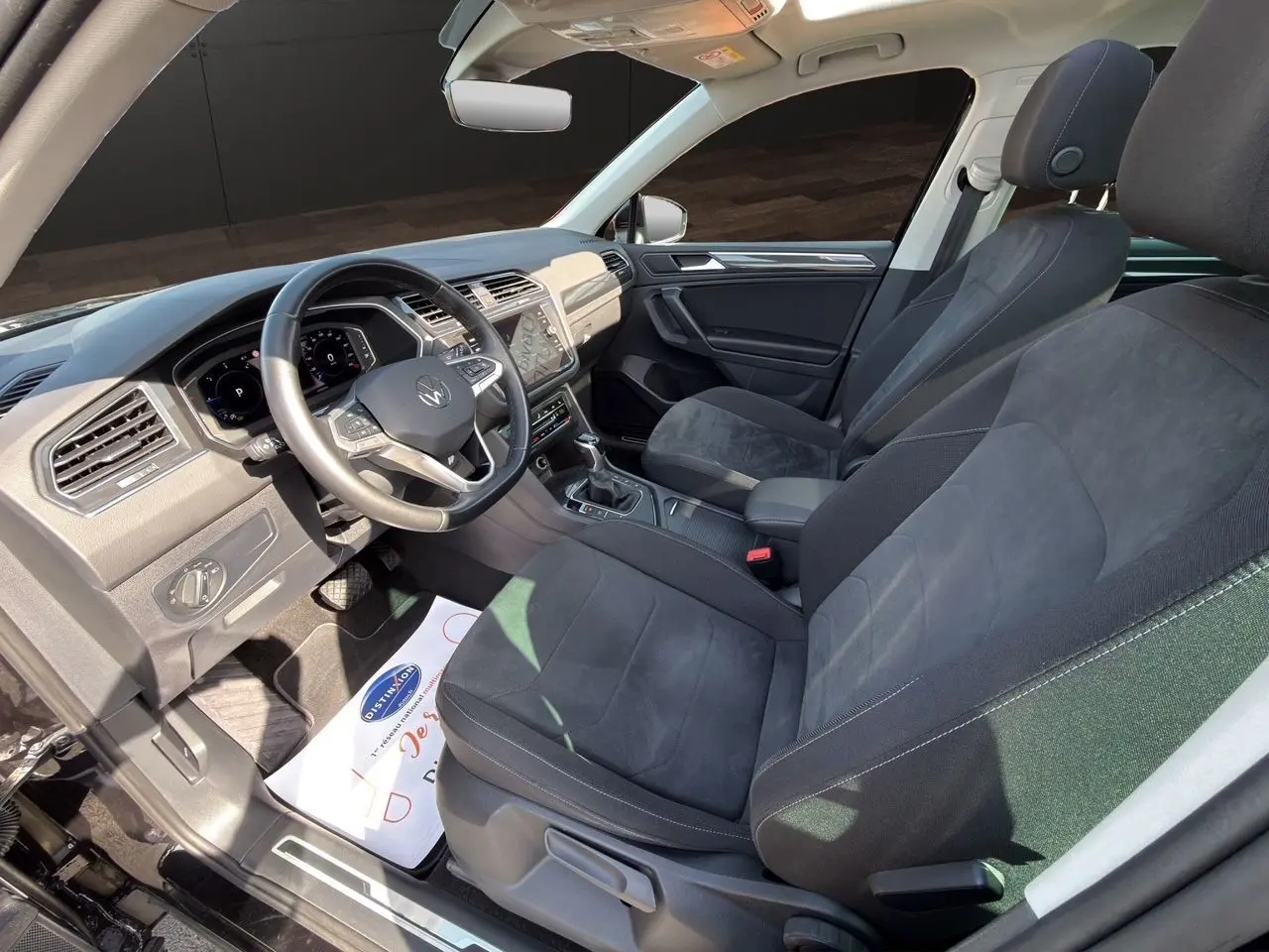 Vue intérieure avant droite du Volkswagen Tiguan 2.0 TDI 2022 avec sièges tissu noir et tableau de bord moderne.
