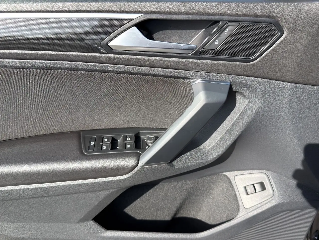 Vue rapprochée de la porte avant gauche noire intense du Volkswagen Tiguan 2022 avec commandes de vitres et verrouillage.