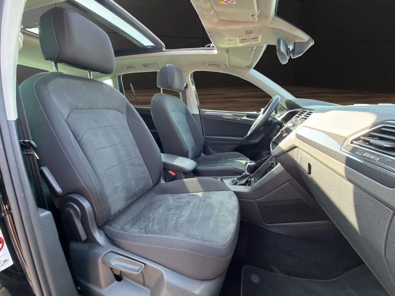 Vue intérieure côté gauche du Volkswagen Tiguan 2.0 TDI 150 DSG7 Elegance 2022 avec toit panoramique et sièges tissu noir.