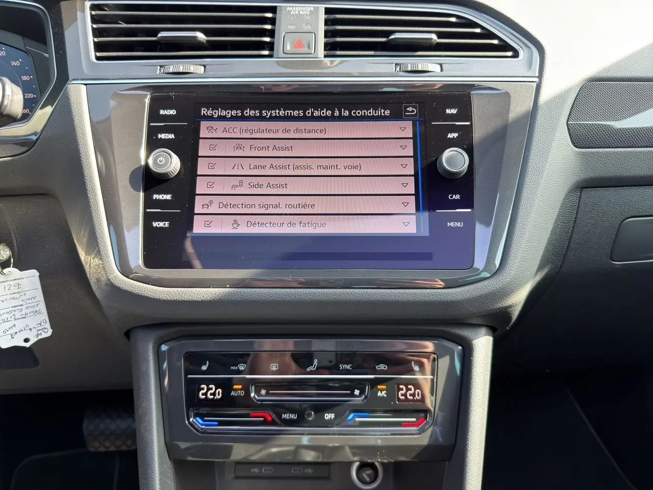 Vue rapprochée du tableau de bord noir du Volkswagen Tiguan 2022 avec écran tactile affichant les aides à la conduite.