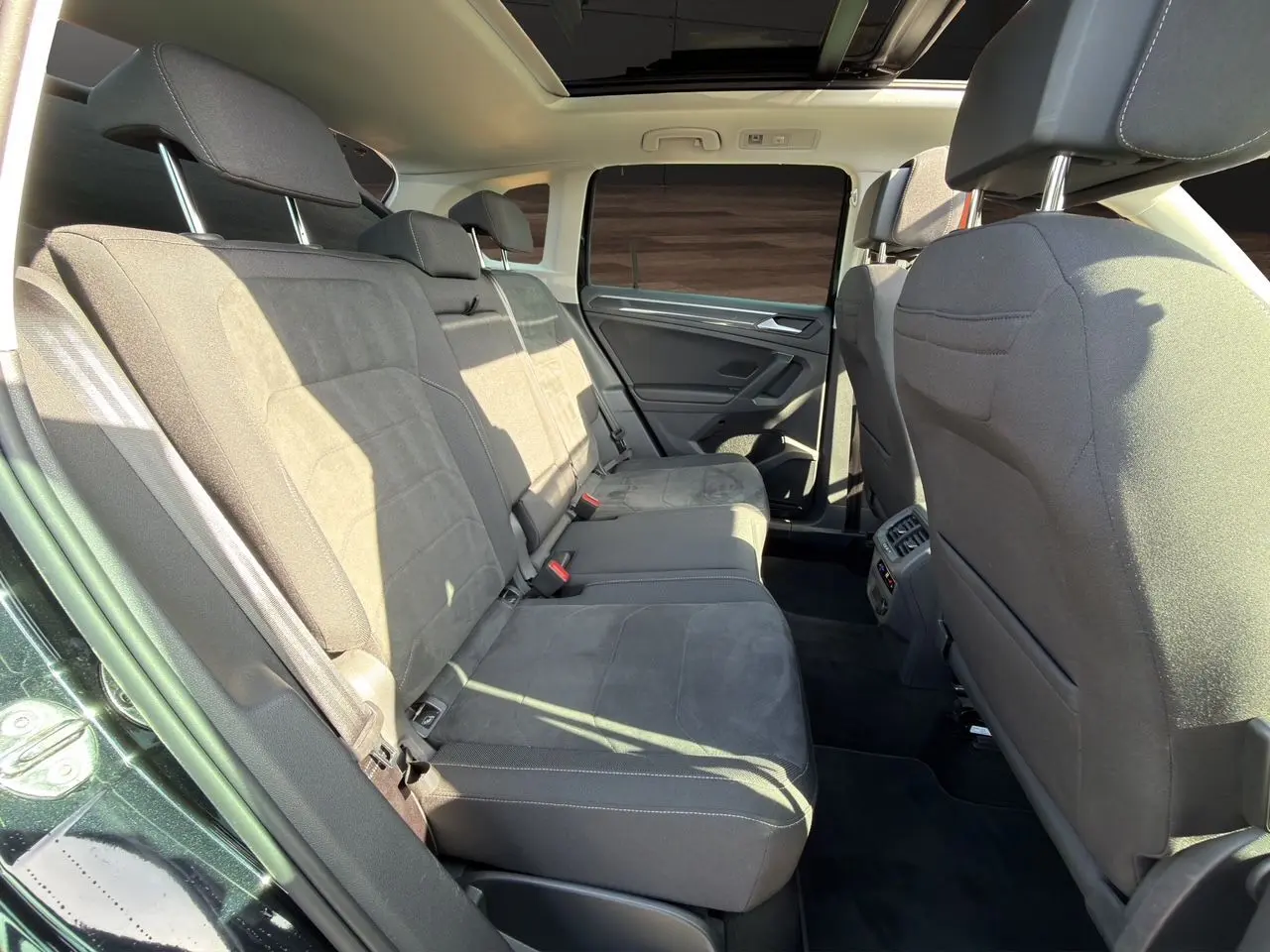 Vue intérieure arrière du Volkswagen Tiguan noir intense 2022, montrant les sièges arrière en tissu noir et toit panoramique.