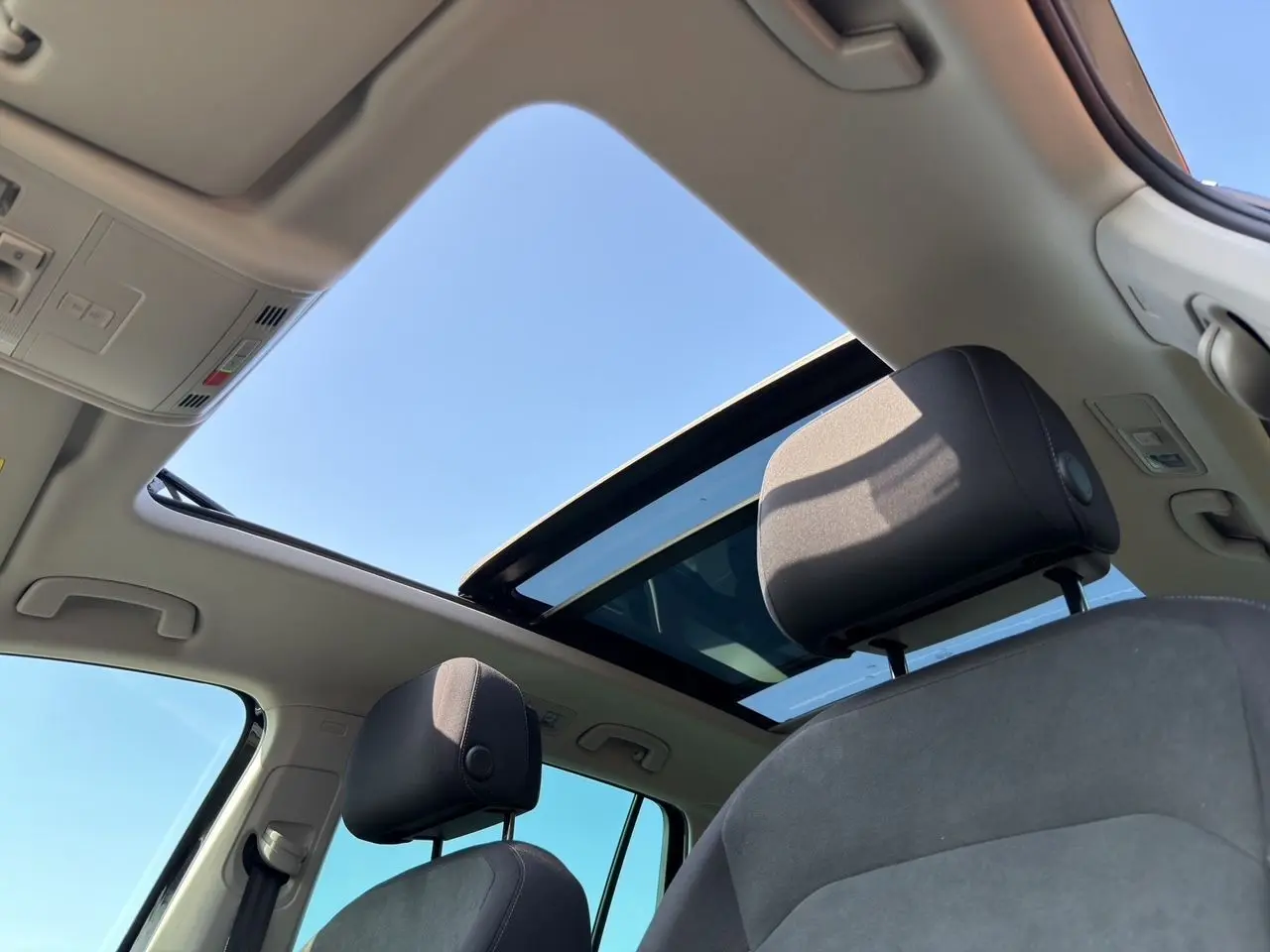 Vue intérieure du Volkswagen Tiguan 2022 noir intense, toit panoramique ouvert et sièges avant en tissu noir.