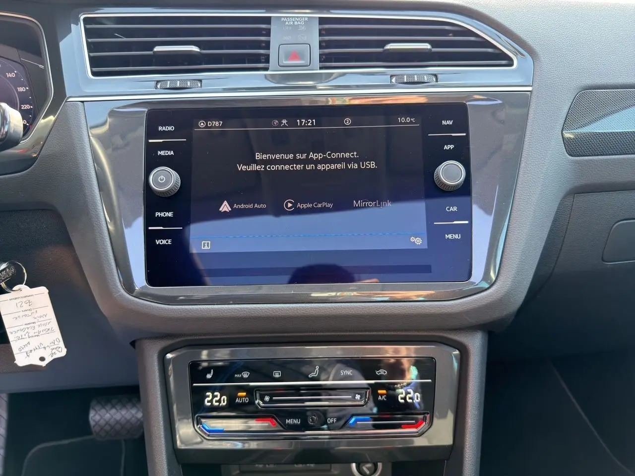 Vue intérieure du tableau de bord du Volkswagen Tiguan 2022, écran tactile et commandes climatisation en noir.