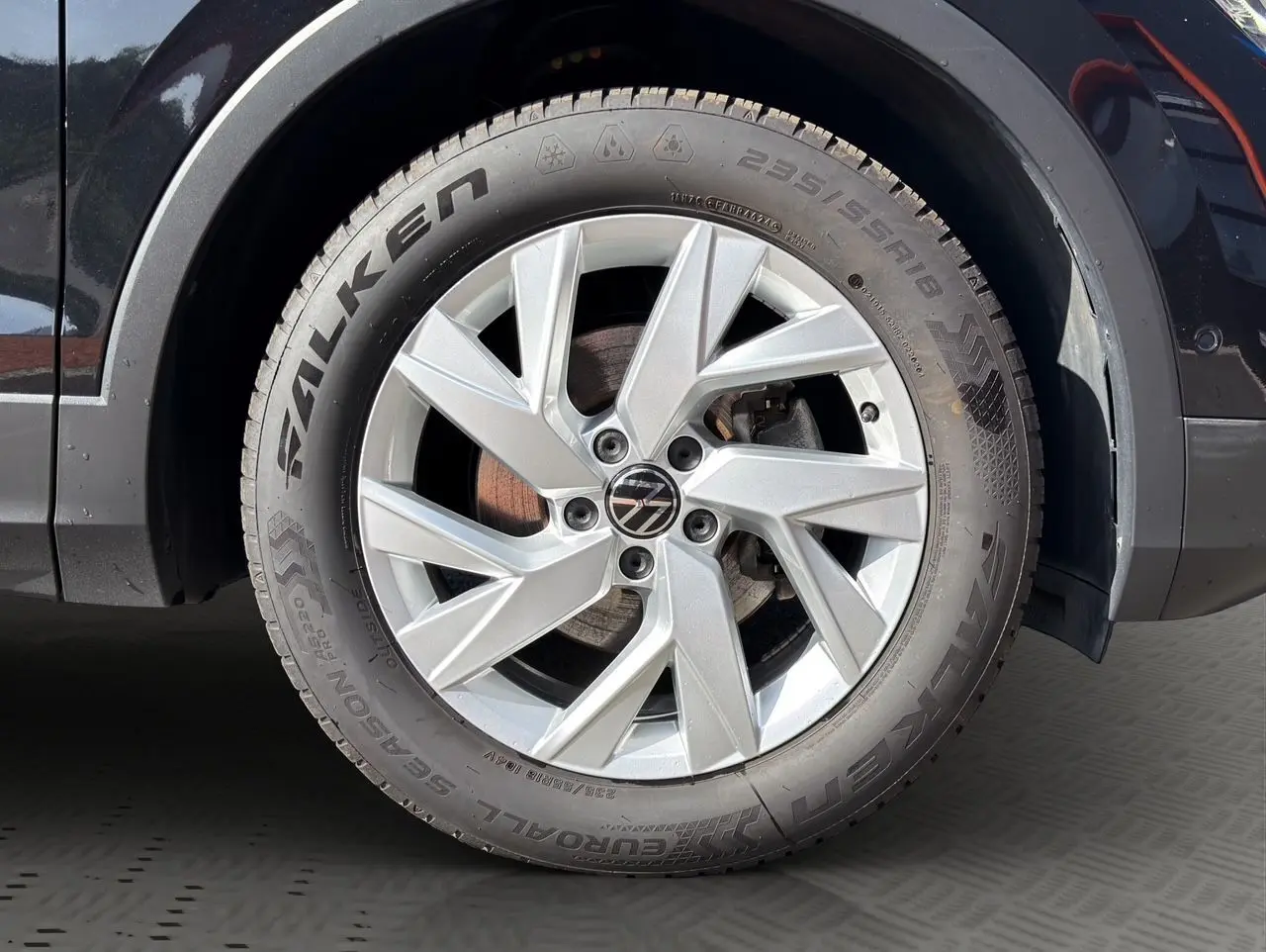 Gros plan sur la roue avant gauche d’un Volkswagen Tiguan noir intense avec jante alu 18 pouces et pneu Falken.