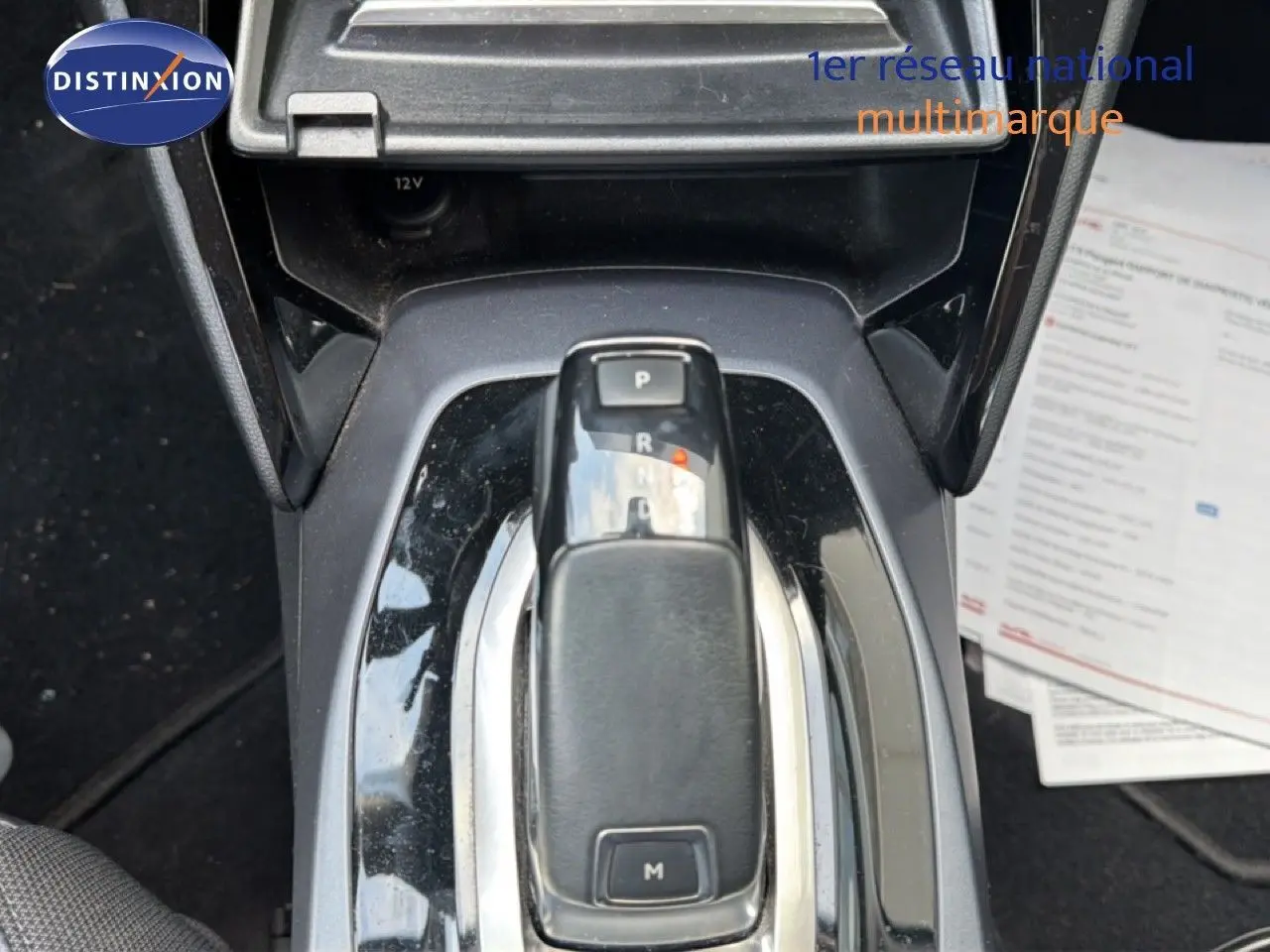 Le levier de vitesses automatique en gros plan au centre de la console d'une Peugeot 2008 rouge avec toit noir.