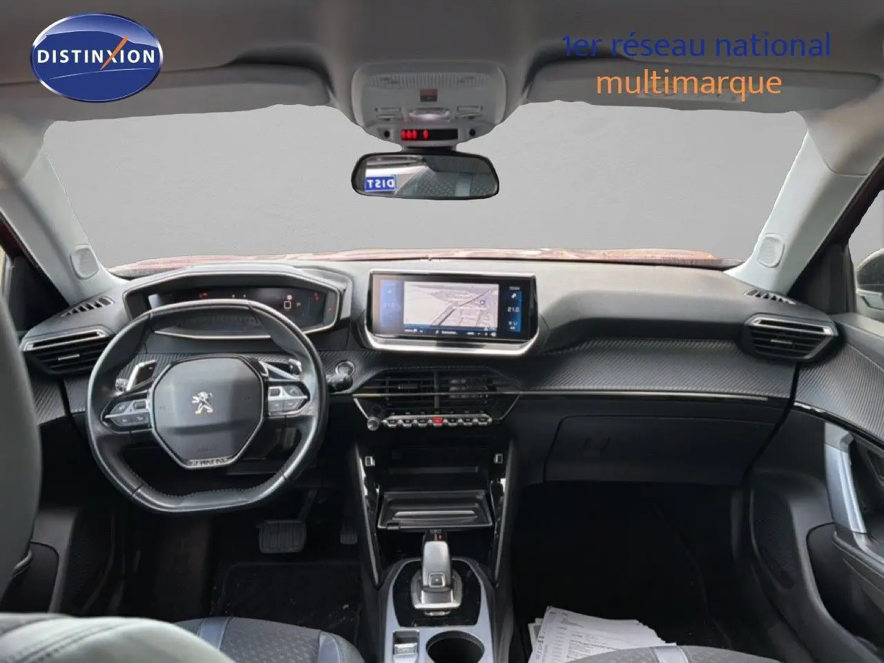 Vue intérieure avant du Peugeot 2008 rouge avec toit noir, montrant le tableau de bord et l'écran central tactile.