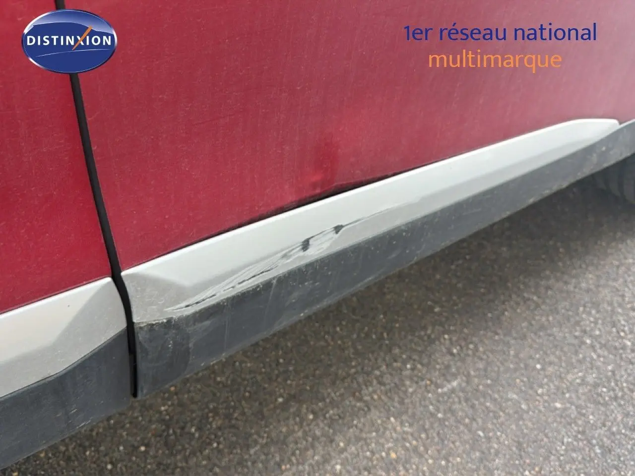 Gros plan sur la partie basse côté gauche d’une Peugeot 2008 rouge avec toit noir, montrant une rayure sur le bas de caisse.