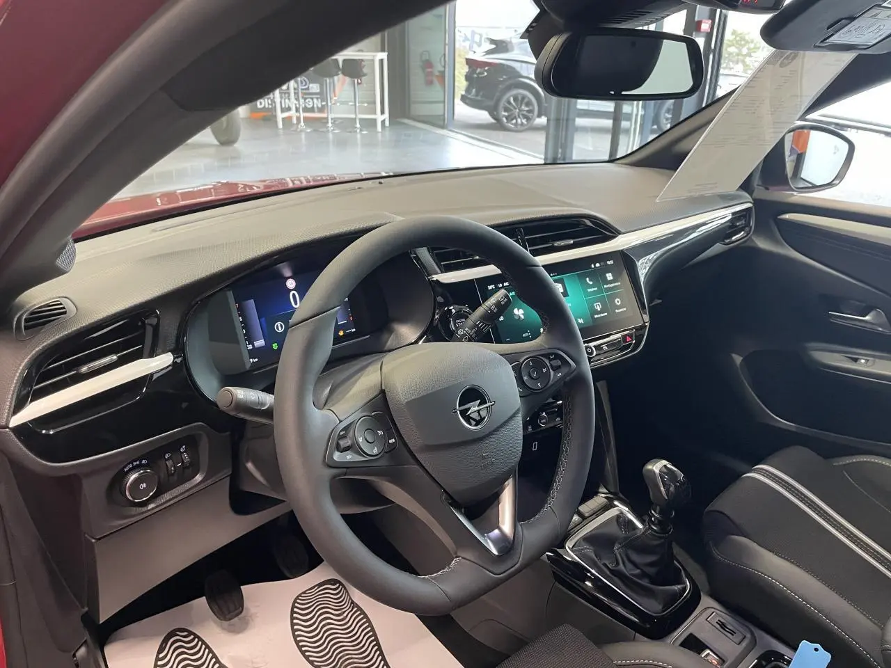 Vue intérieure côté conducteur de l’Opel Corsa rouge 2026, volant cuir, tableau de bord numérique et écran tactile 10 pouces.