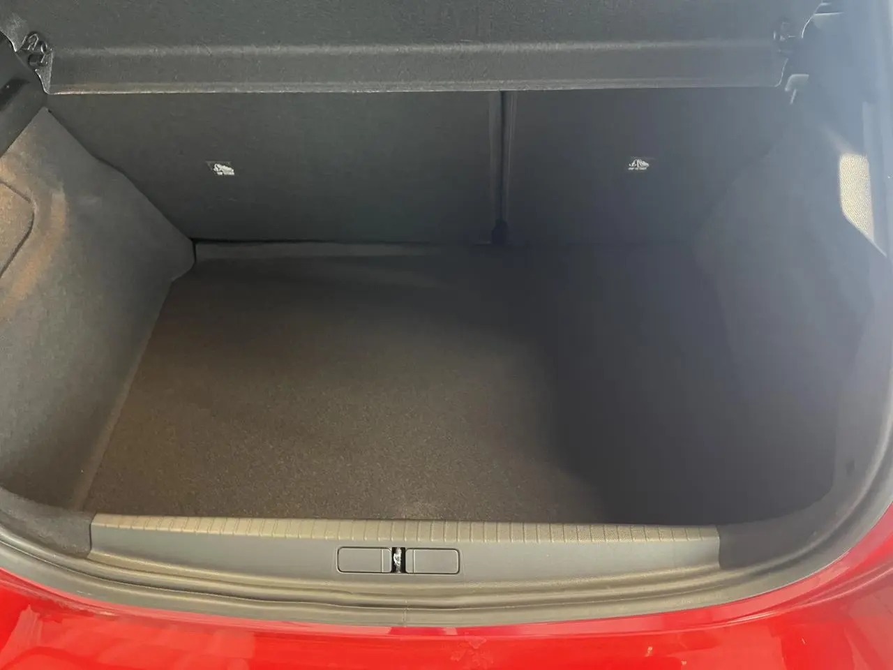 Coffre ouvert vu de face d’une Opel Corsa rouge 2026, intérieur noir et seuil de coffre gris.