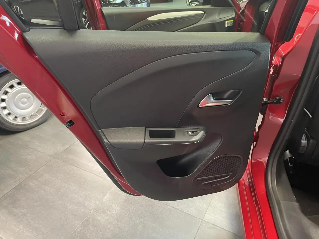 Vue rapprochée de la porte arrière gauche rouge d’une Opel Corsa 2026, avec panneau intérieur noir et poignée argentée.