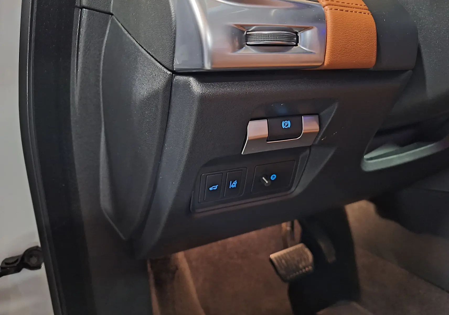 Détail du tableau de bord côté gauche du Jaguar E-PACE blanc 2019 avec commandes éclairées et insert cuir marron.