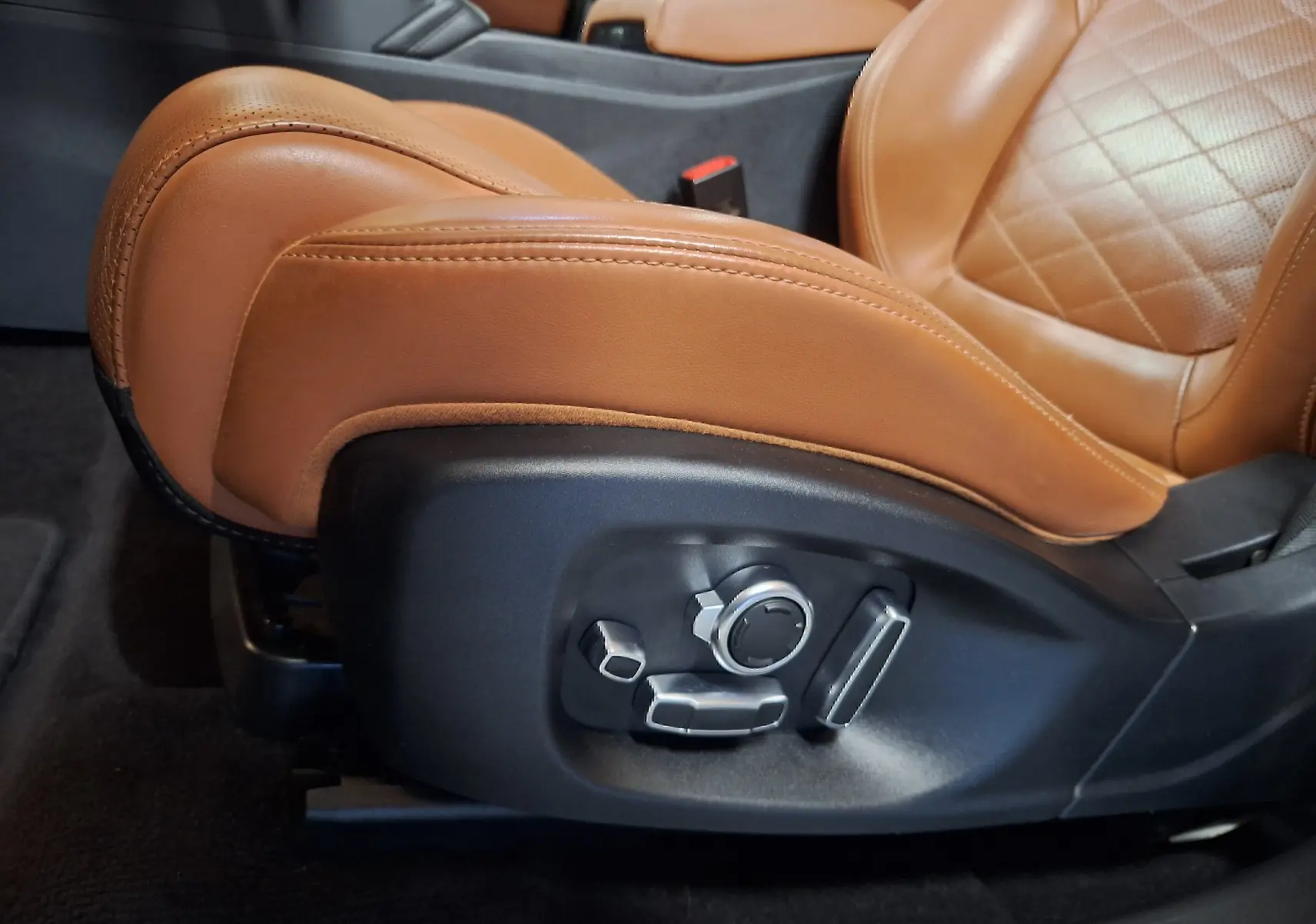 Gros plan sur les commandes électriques du siège avant en cuir marron du Jaguar E-PACE blanc 2019.