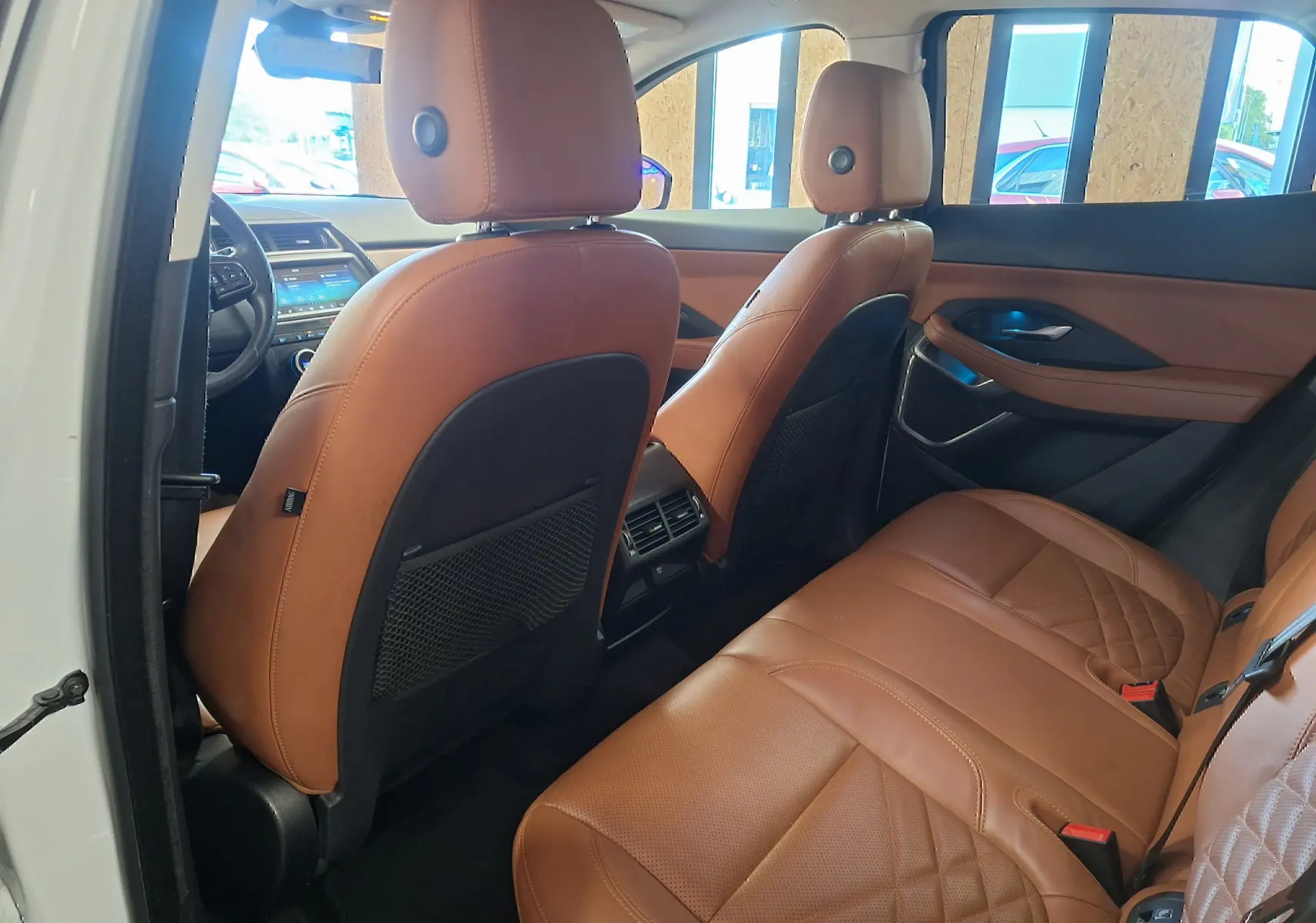 Vue intérieure arrière du Jaguar E-PACE blanc 2019 avec sièges en cuir marron et détails de porte assortis.