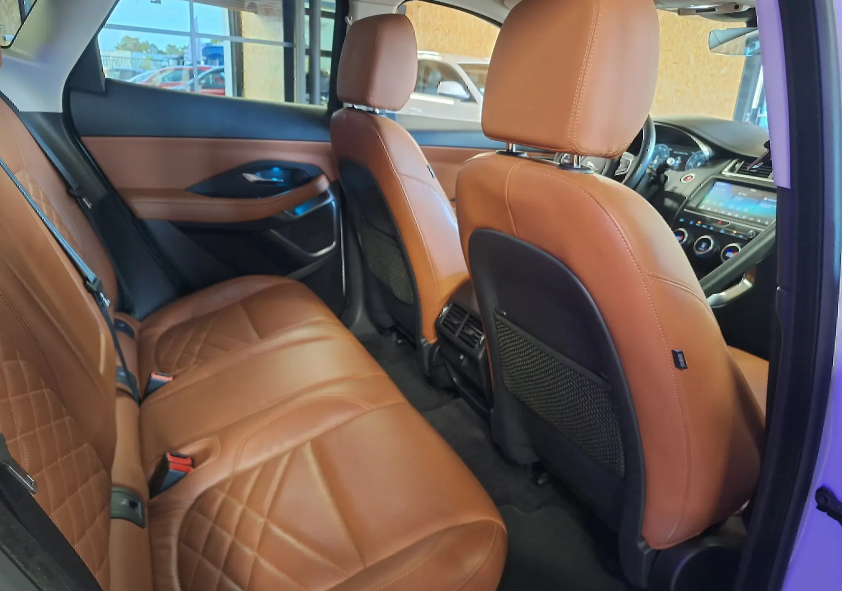 Intérieur arrière du Jaguar E-PACE 2019 avec sièges en cuir marron et tableau de bord visible côté conducteur.