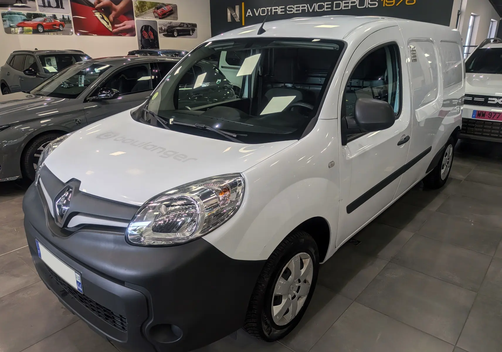 Renault Kangoo Express blanc minéral en 3/4 avant droit, avec pare-chocs noir mat et marquage "boulanger" sur le capot.