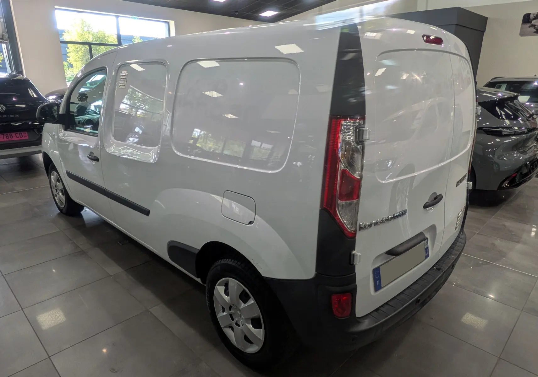 Vue 3/4 arrière droite du Renault Kangoo Express blanc minéral, fourgon utilitaire avec hayon arrière fermé en intérieur showroom.