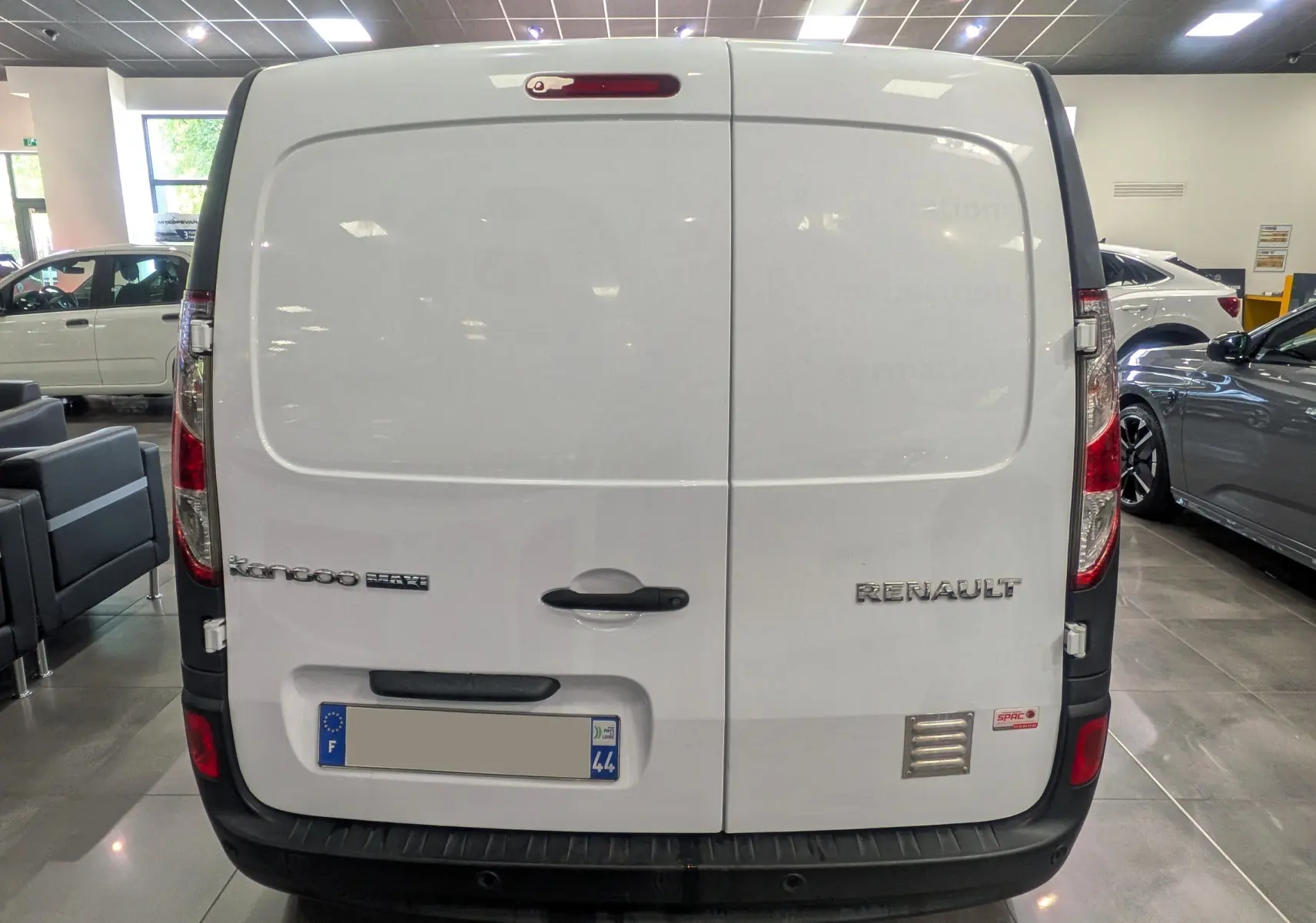 Vue arrière d’un Renault Kangoo Express blanc minéral, version Grand Volume, avec portes battantes et logo visible en concession.