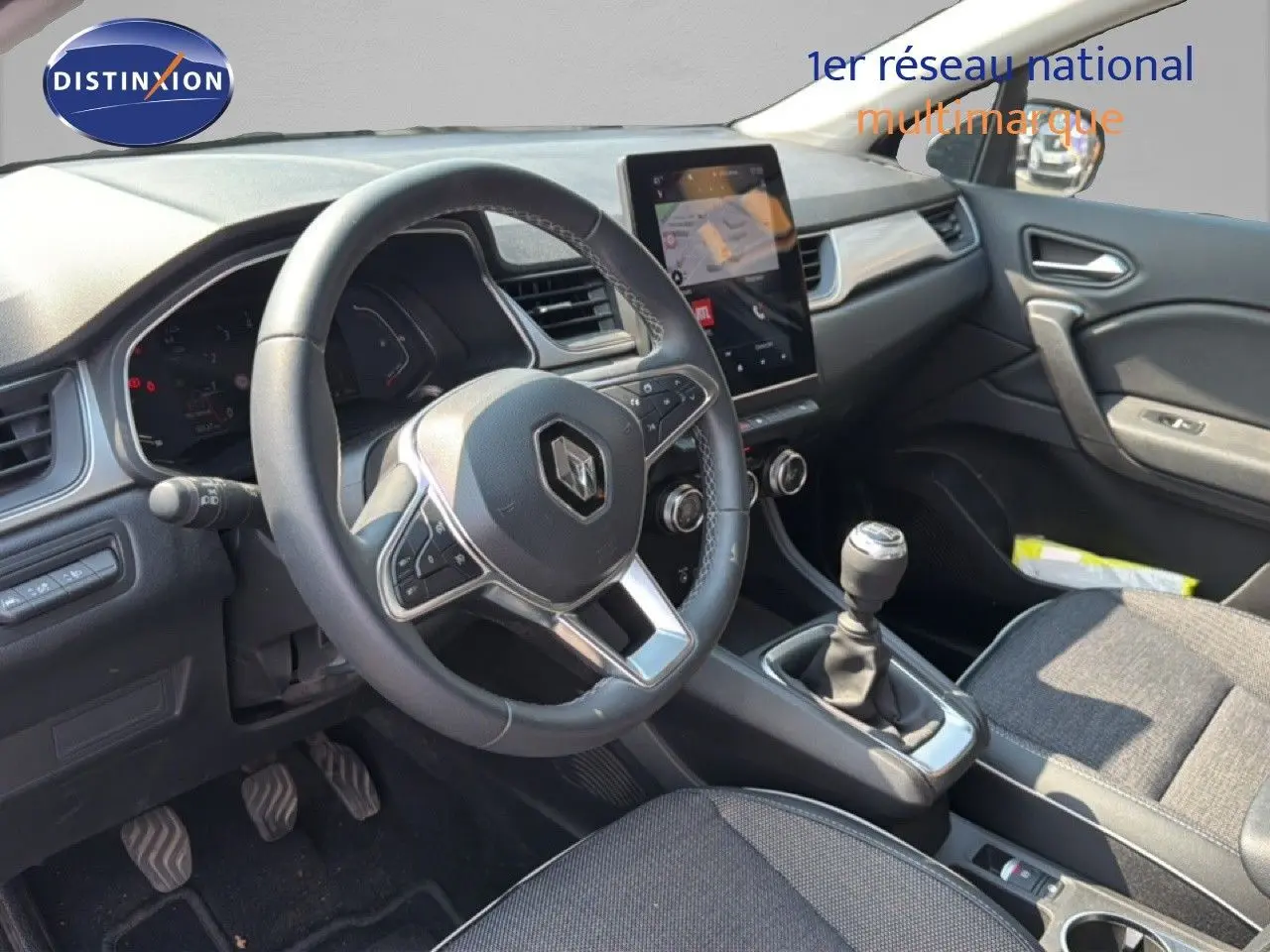 Vue intérieure côté conducteur du Renault Captur 2022 bleu marine fumé, avec volant multifonction et boîte manuelle.