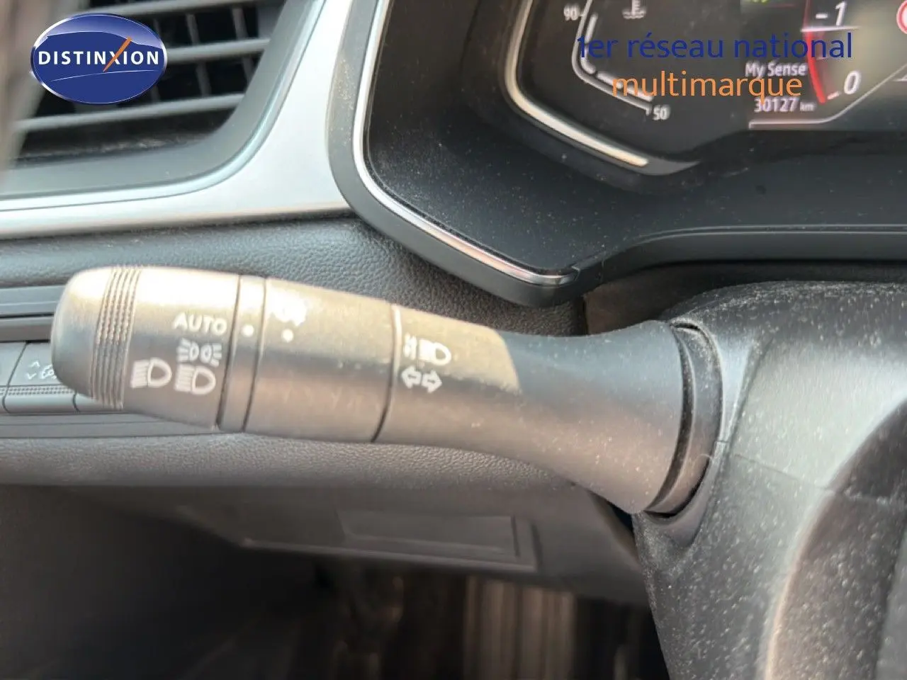 Gros plan sur la manette de clignotant à gauche du volant dans l'habitacle du Renault Captur bleu marine fumé.